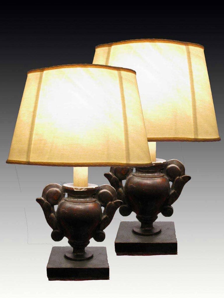 A pair of early 19th century Italian silver-leaf wooden small table lamps, consisting of two antique portapalme vases, on square base, turned Cembran pinewood with shaped handles.
Mounted as small lamps with new oval-shaped demi-lune lampshades