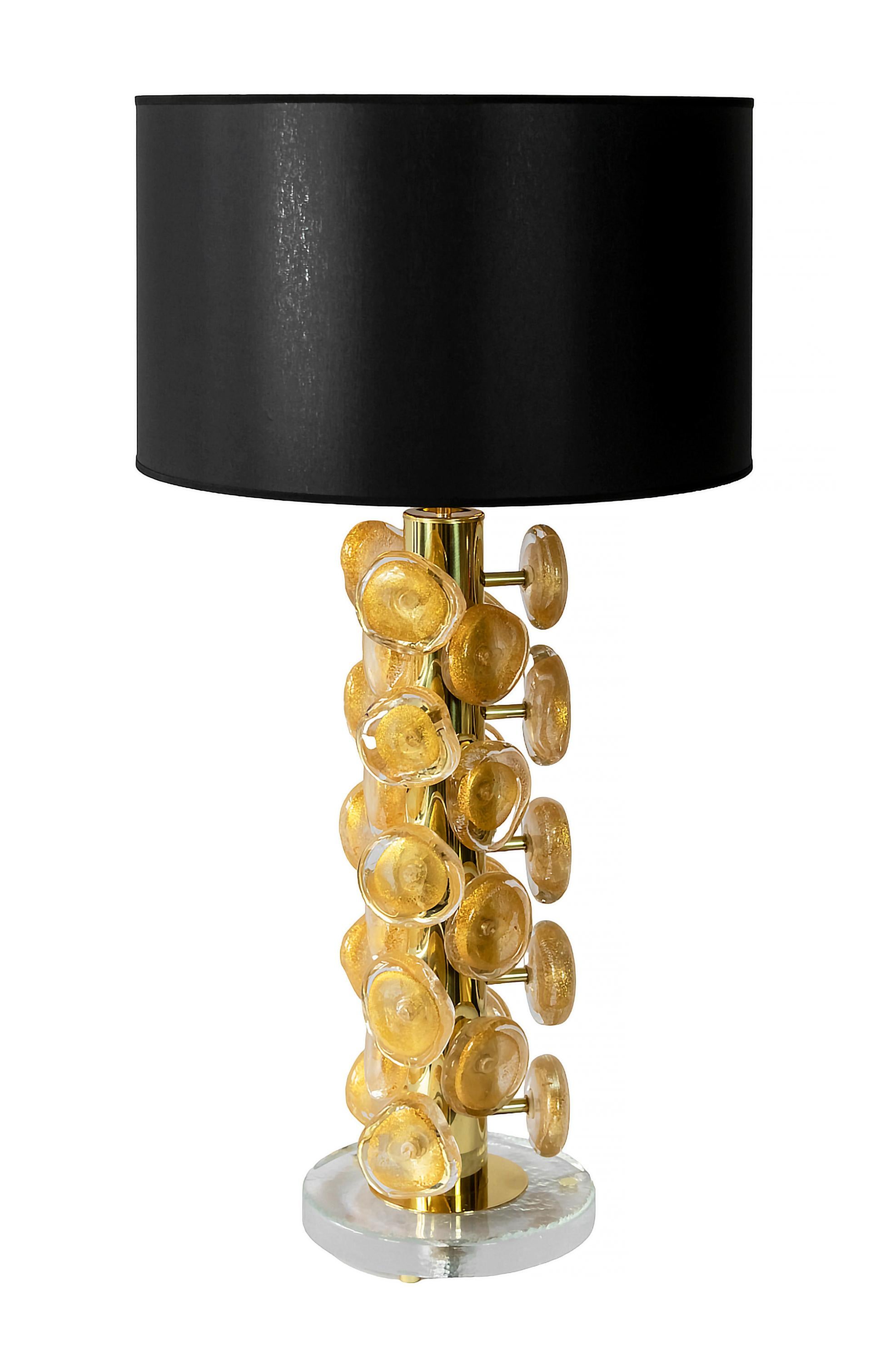 Pair of Italian table lamps made in brass and thick glass base with brass legs.
Decorated with clear and gold dust inside Murano glass details. Each glass detail is handmade in asymmetric form of approx. 9.5 cm diameter.
Both lamps are with new