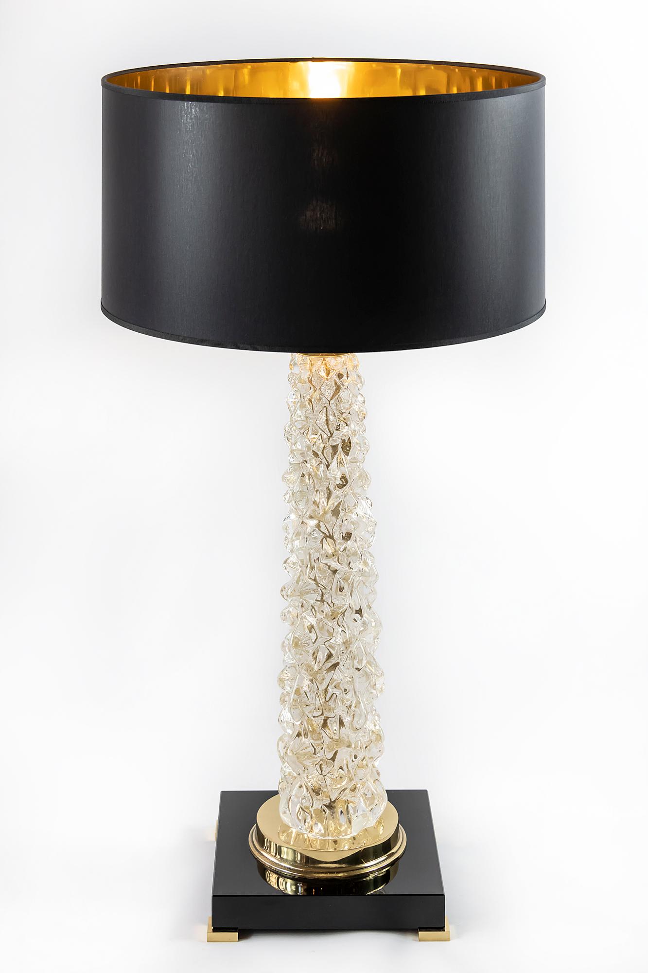 This pair of Italian table lamps are made of transparent Murano glass. The base is made of rectangular thick black glass with small brass legs. Decorated with polished brass details. Both lamps are with new made satin finish black color textile