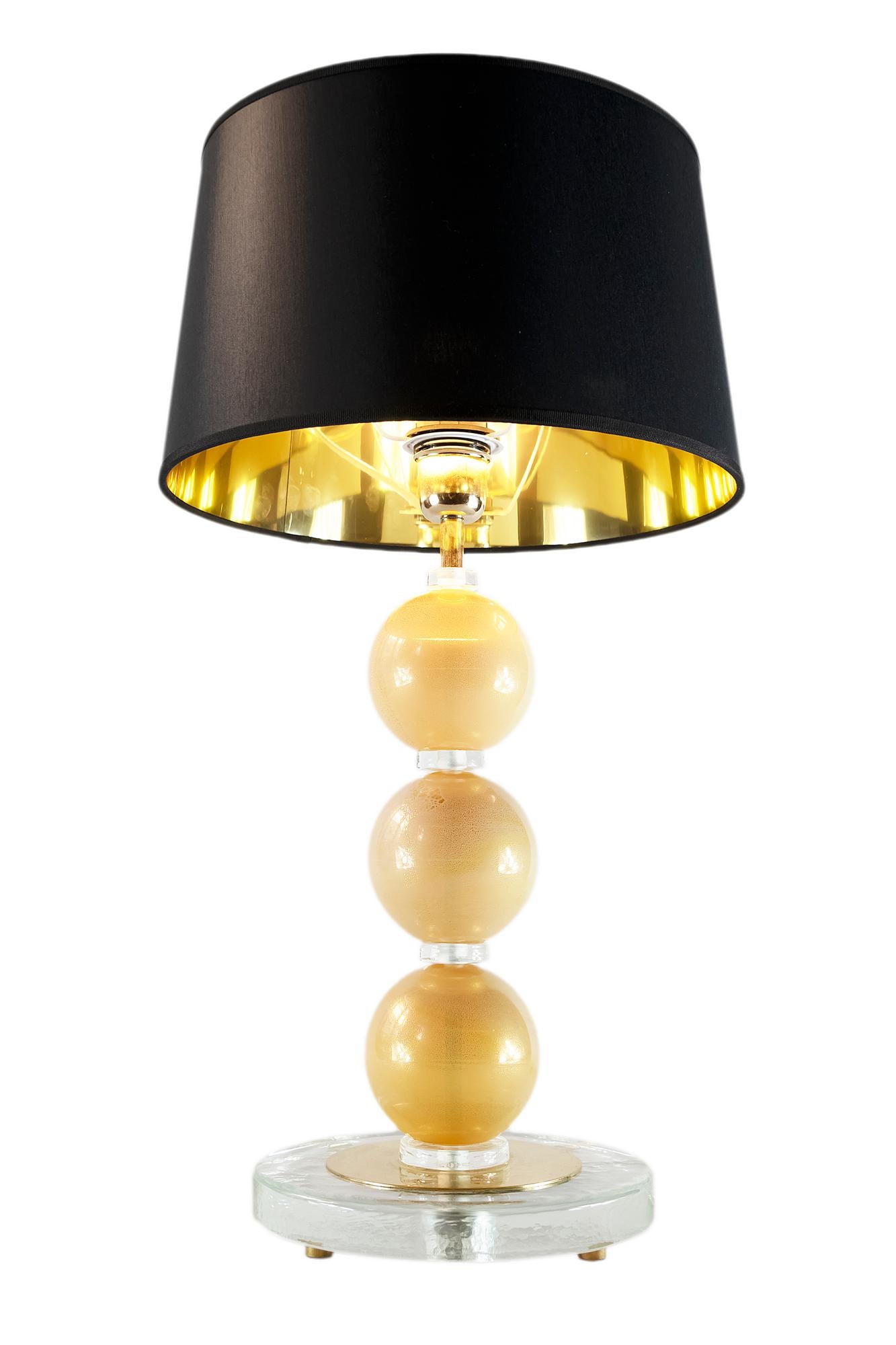 This pair of Italian table lamps are designed in Murano glass.
The glass is lightly yellow with inlaid gold.
The base is made of round form thick clear glass with small round brass legs.
Both lamps are with new made satin finish black color