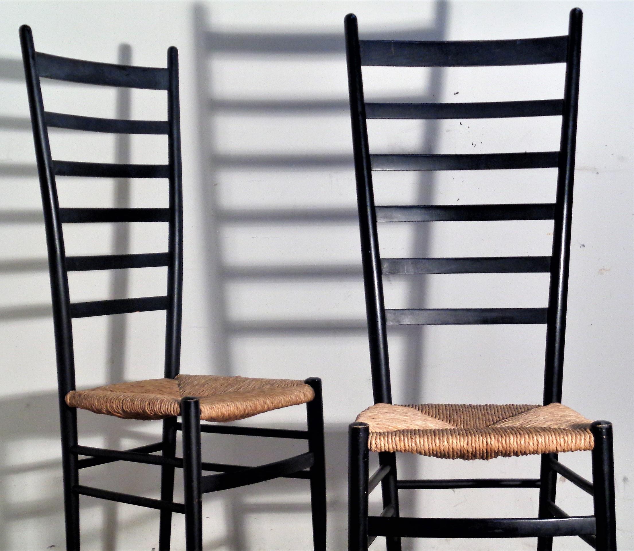 In the modernist style of Gio Ponti, a pair of tall ladder back chairs with original black ebonized wood frames and woven rush seats. Stamped Italy inside of upper rear stretcher. Circa 1960. Look at all pictures and read condition report in comment