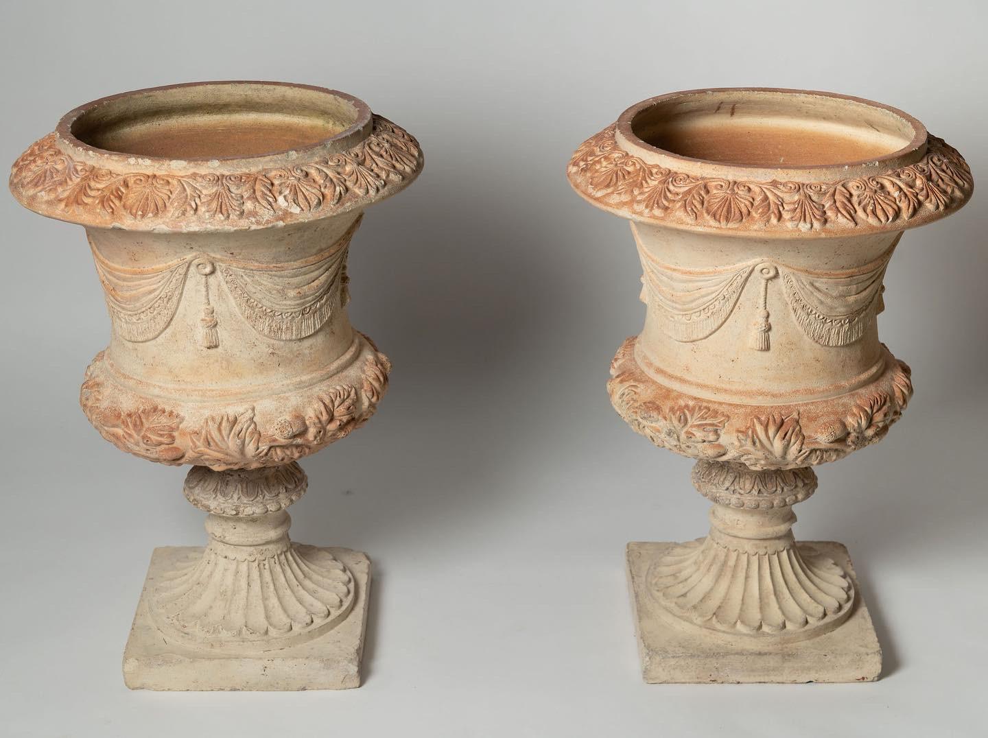 A lovely pair of Italian terracotta urns, swags and acorns. Perfect for the home or garden. They are in two sections per urn. (Base and urn) Soft colour tones. The base is 11.5 inches x 11.5 inches. Age related wear, chips etc, no cracks or