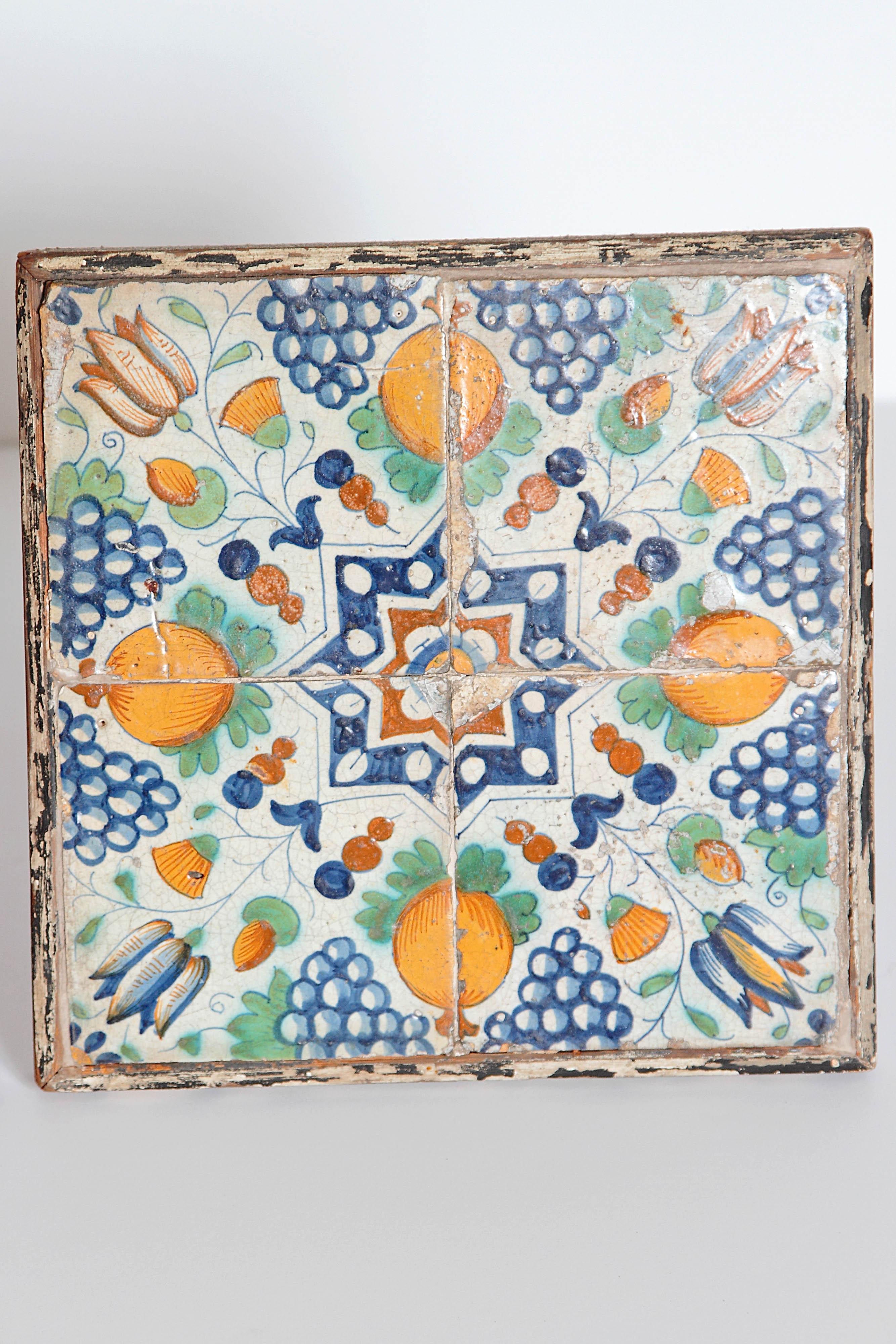 A pair of antique terra cotta Italian tiles. This set of tiles has a vibrant color scheme of orange, green and blue on a white background. Each consist of four tiles set in a weathered wooden frame. These tiles would be great either on the wall or