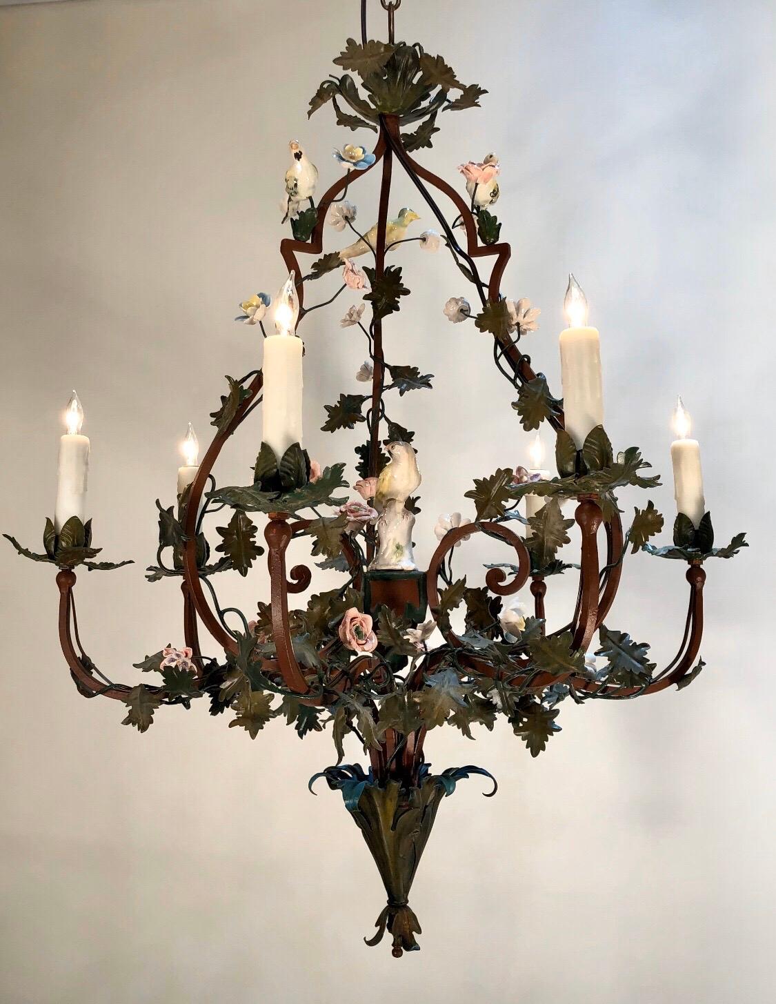 Elegant pair of Tôle cage form Louis XIV six arm chandeliers in the chinoiserie style. Each chandelier has a hand painted iron cage wrapped in vines with Tôle leaves and hand painted porcelain flowers in three styles. The center of the chandeliers