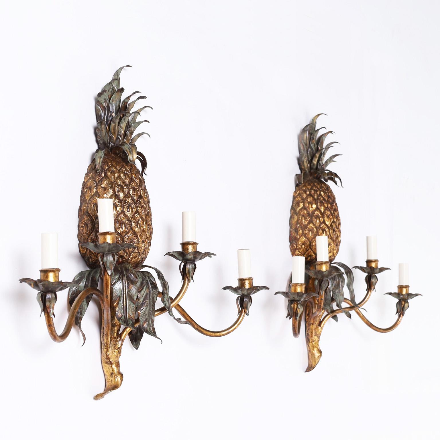 Pair of Italian vintage tole or painted metal wall sconces having pineapples over four graceful arms with floral bobeches.