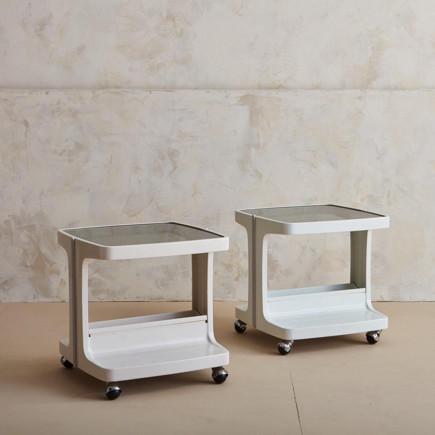 Una coppia di tavolini da bar in acrilico bianco sporco su ruote con piani in vetro fumé e un elegante bordo verticale grigio su entrambi i lati. Attribuito al designer industriale italiano Joe Colombo (1930-1971).