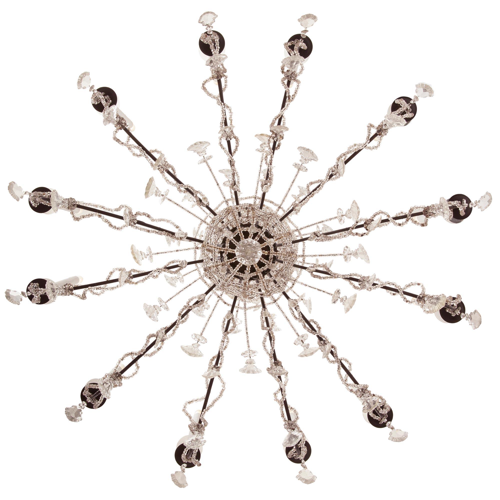 A stunning and extremely decorative pair of Italian turn of the century iron and crystal Venetian st. chandeliers. Each twelve arm chandelier is centered by a beautiful diamond shaped cut crystal pendant below a lovely array of cut crystal pendants