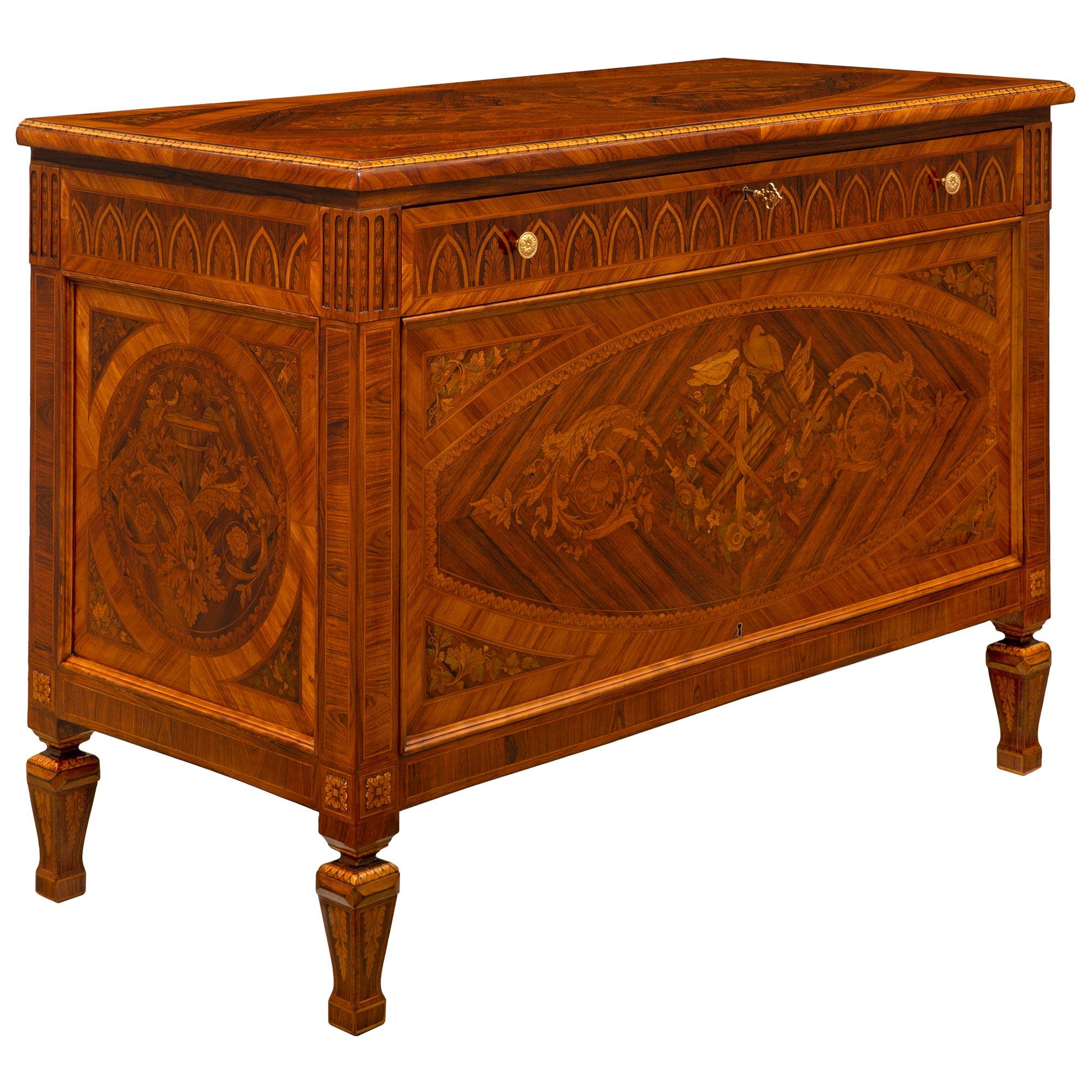 An elegant pair of Italian turn of the century Louis XVI st. Kingwood, Tulipwood, and Charmwood commodes. Each three drawer one door chest is raised by fine square tapered legs with a mottled design and lovely foliate inlays. At the center is a door