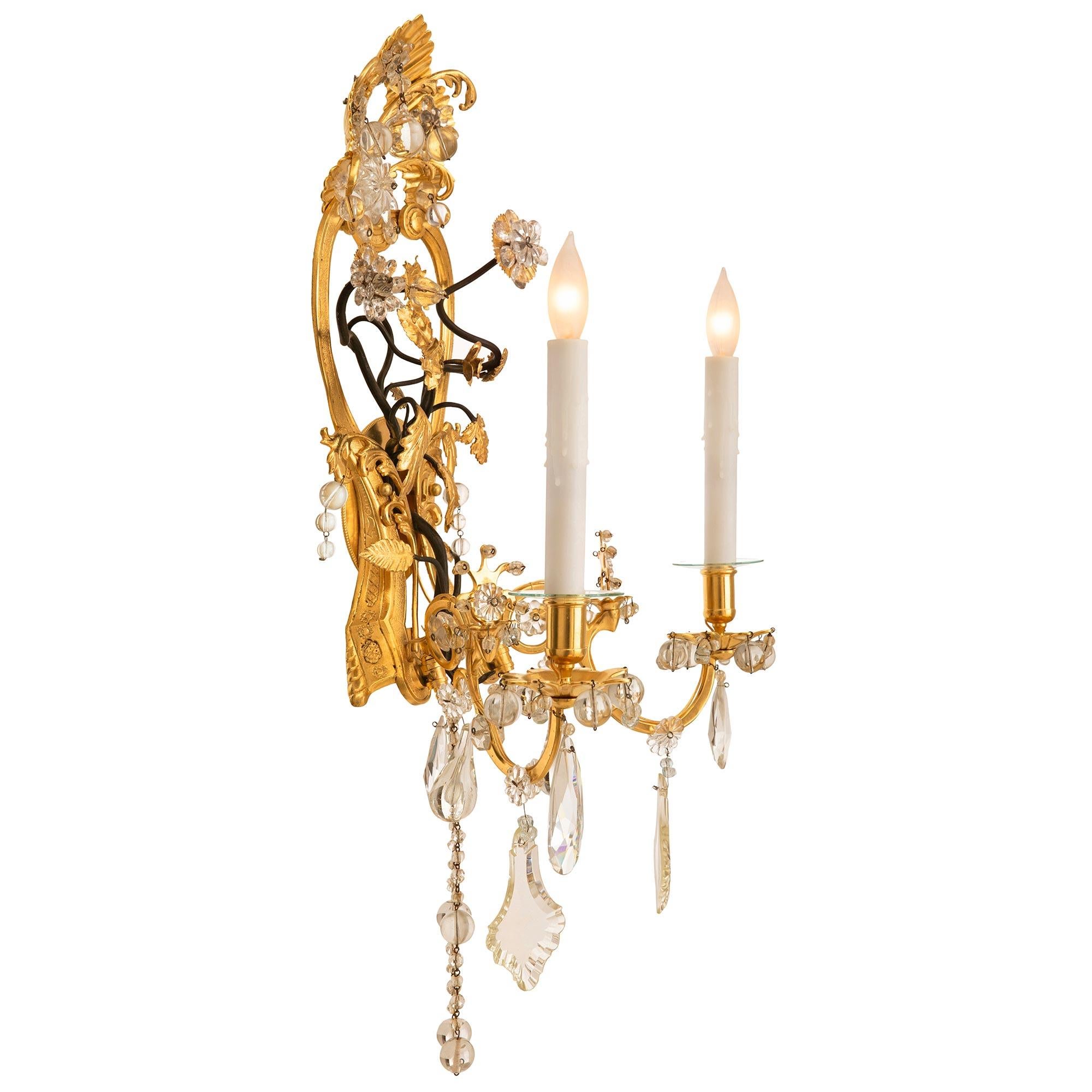 An exceptional and very unique pair of Italian turn of the century Louis XVI st. ormolu and crystal sconces. Each two arm sconce displays a striking pierced backplate with a beautiful and most elegant scrolled shape with a stunning reeded seashell