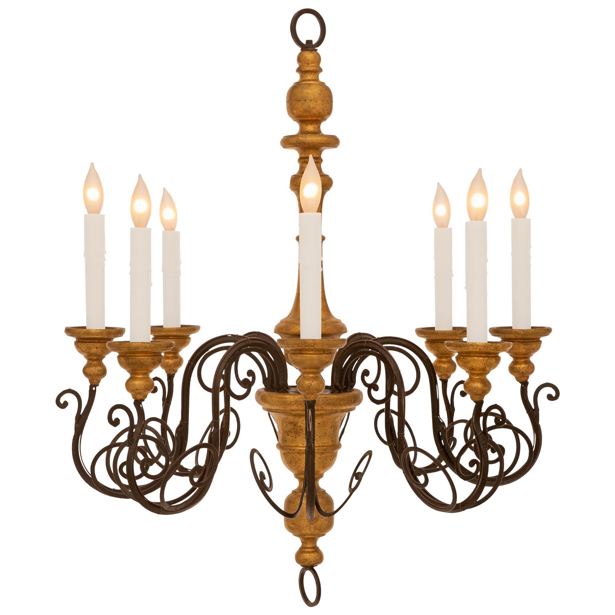 A very decorative pair of Italian turn of the century Wrought Iron and Giltwood chandeliers. The pair of eight arm chandeliers have central turned Giltwood futs with Wrought Iron protruding arms at the mid sections. Each 'S' scrolled Wrought Iron