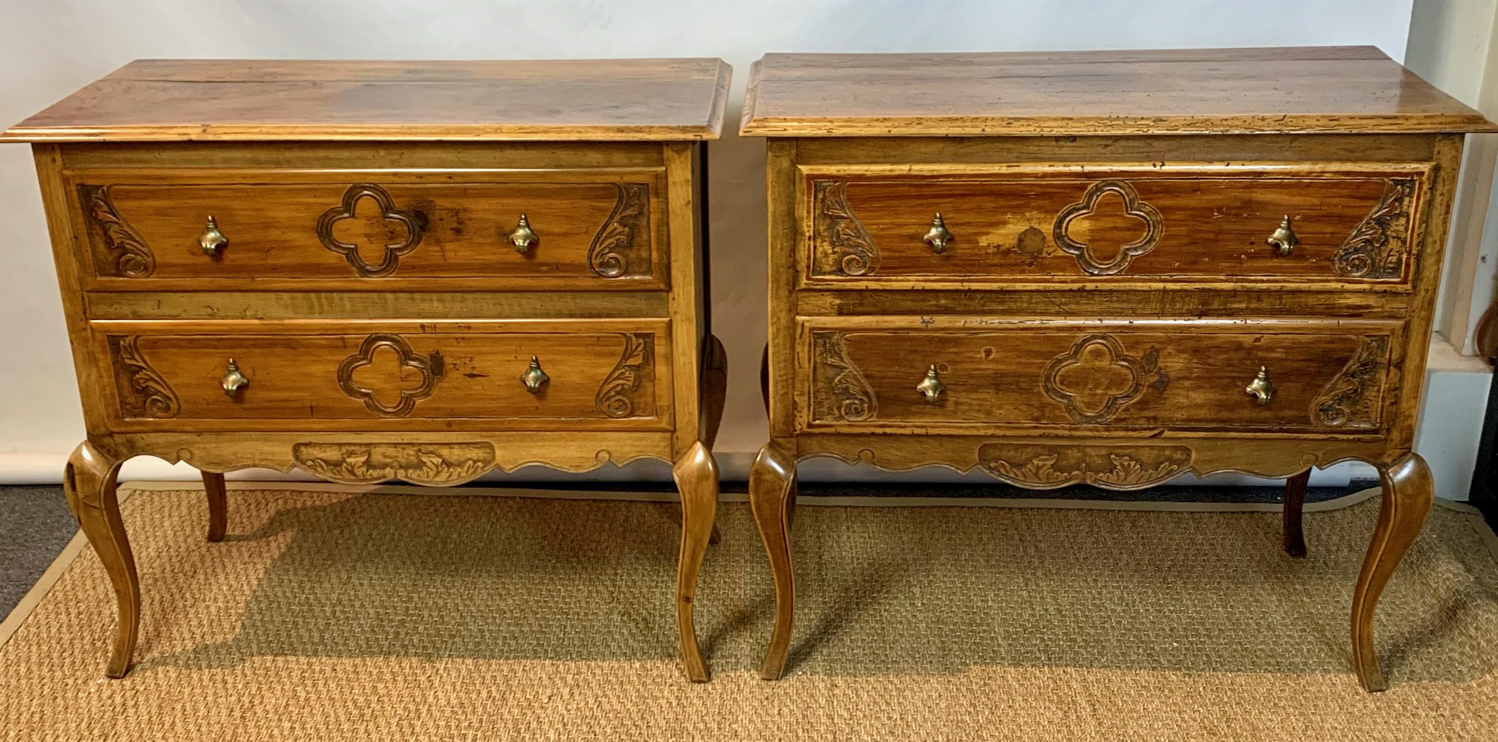 An attractive near pair of early 20th century Italian fruitwood two-drawer chests or bedside tables beautifully carved with inset acanthus leaves and clover designs with brass pulls over a scrolling apron terminating in shapely cabriole legs.