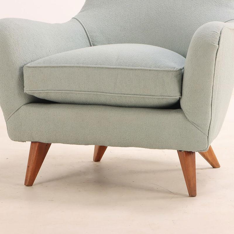 Esta encantadora pareja de sillas club de los años 50 presenta líneas elegantemente curvadas y una silueta grácil y orgánica. Recién tapizadas en suave tela gris pálido y colocadas sobre clásicas patas de madera, estas sillas compactas combinan el