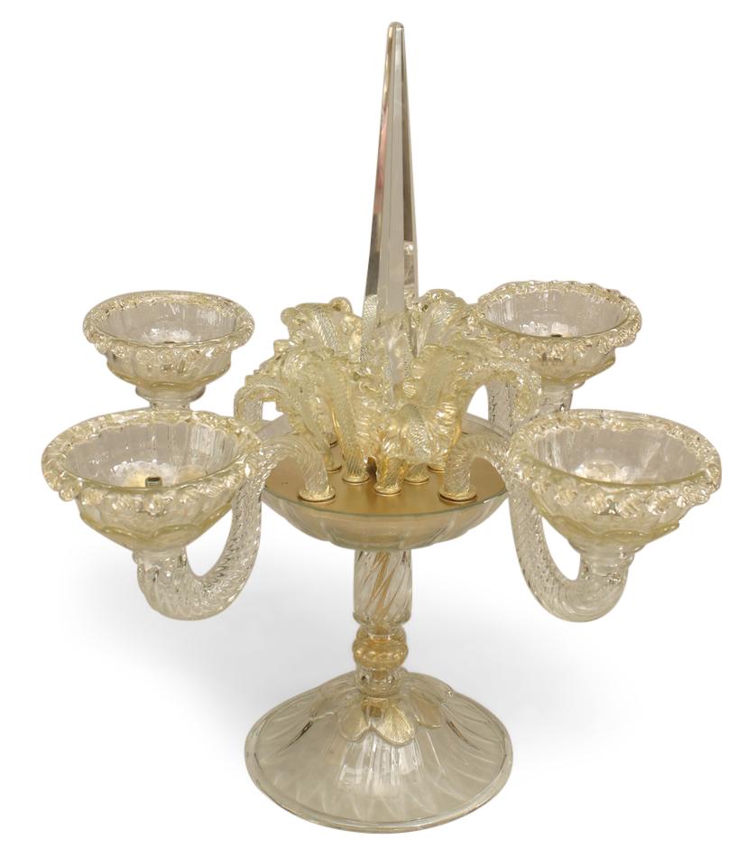 Pair of Italian Venetian Murano (20th century) clear and gold dusted glass candelabras with 4 swirl arms and a center obelisk surrounded by glass leaves raised on a pedestal base (after a model designed by ANDRE ARBUS). (priced as pair).
      