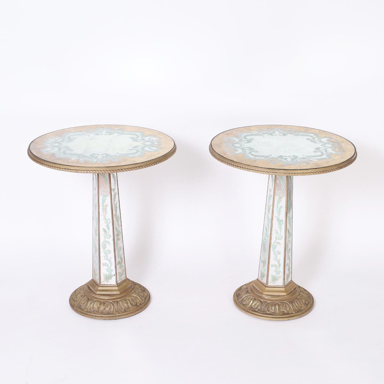 Standout pair of vintage Venetian style stands with round tops decorated in an eglomise technique with floral designs over gold and silver leaf. The hexagon pedestal has leaf designs and sits on a gilt carved wood base. As seen in the last photo of