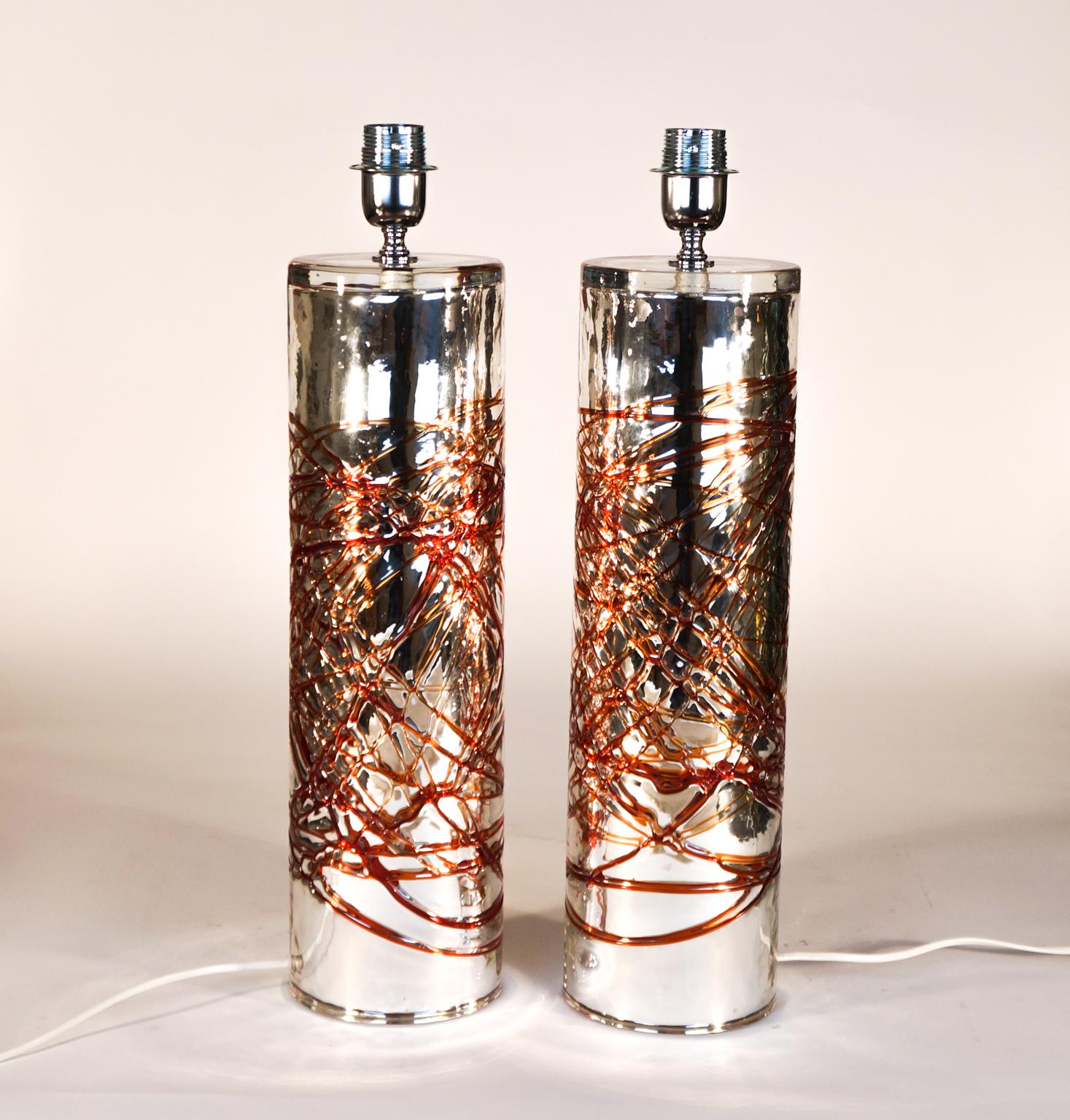Pair of Murano blown glass table lamps, handmade by the famous glass master Alberto Donà.
The two lamps have a cylinder shape with a mirror finish and details in red glass wires
Project of the Murano glass master Alberto Donà in 1990s.
The price