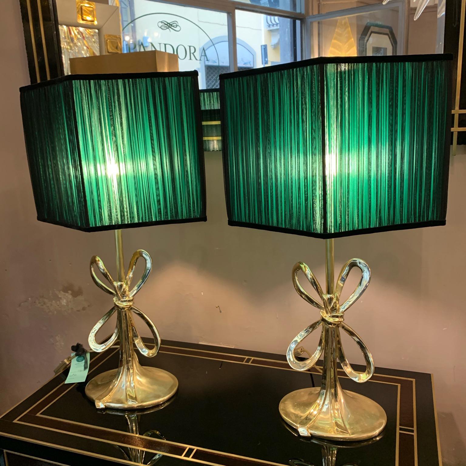 Pair of Italian vintage brass bow table lamps.
The lamps are solid and heavy and they have an oval base. Double color lampshades handmade in our internal laboratory using silk chiffon black on the outside and green on the inside. The colors mixes