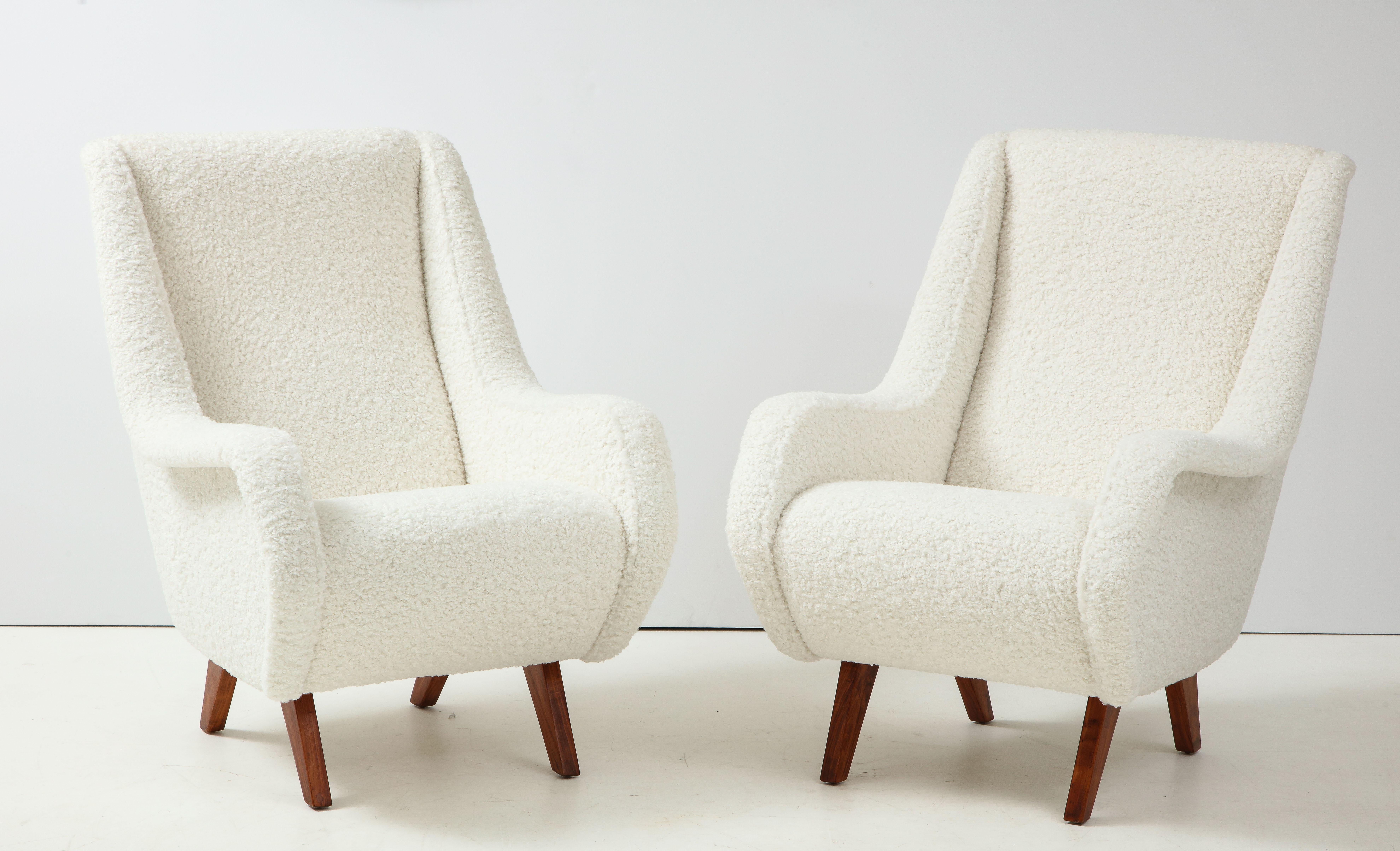 A pair of Italian vintage 1950's lounge chairs with elegantly sloped arm rests extending from the high back, supported on pine legs; the whole newly restructured and re-upholstered in white faux shearling. Extremely comfortable and timeless organic