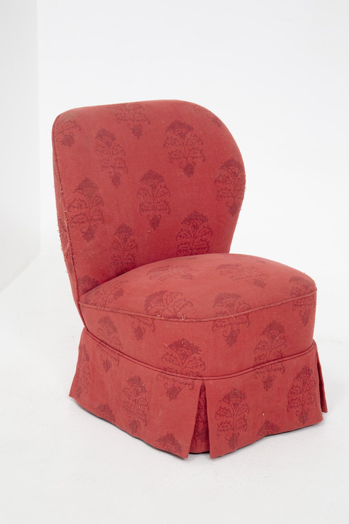 Pair of armchairs from the 50s are in red fabric, with damask details in dark red. The seat is very high and soft, in the same fabric. The backrest is slightly curved and rounded. The base of the armchair is adorned with a unique fringe, with slits