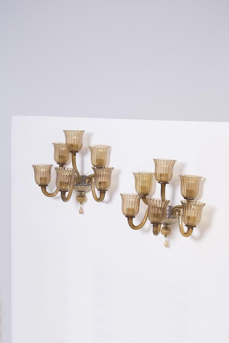 Step into the refined world of 1950s elegance with this exquisite pair of wall lights, crafted by the renowned Venini, a name synonymous with timeless artistry. These wall lights are not just fixtures; they are a celebration of craftsmanship and