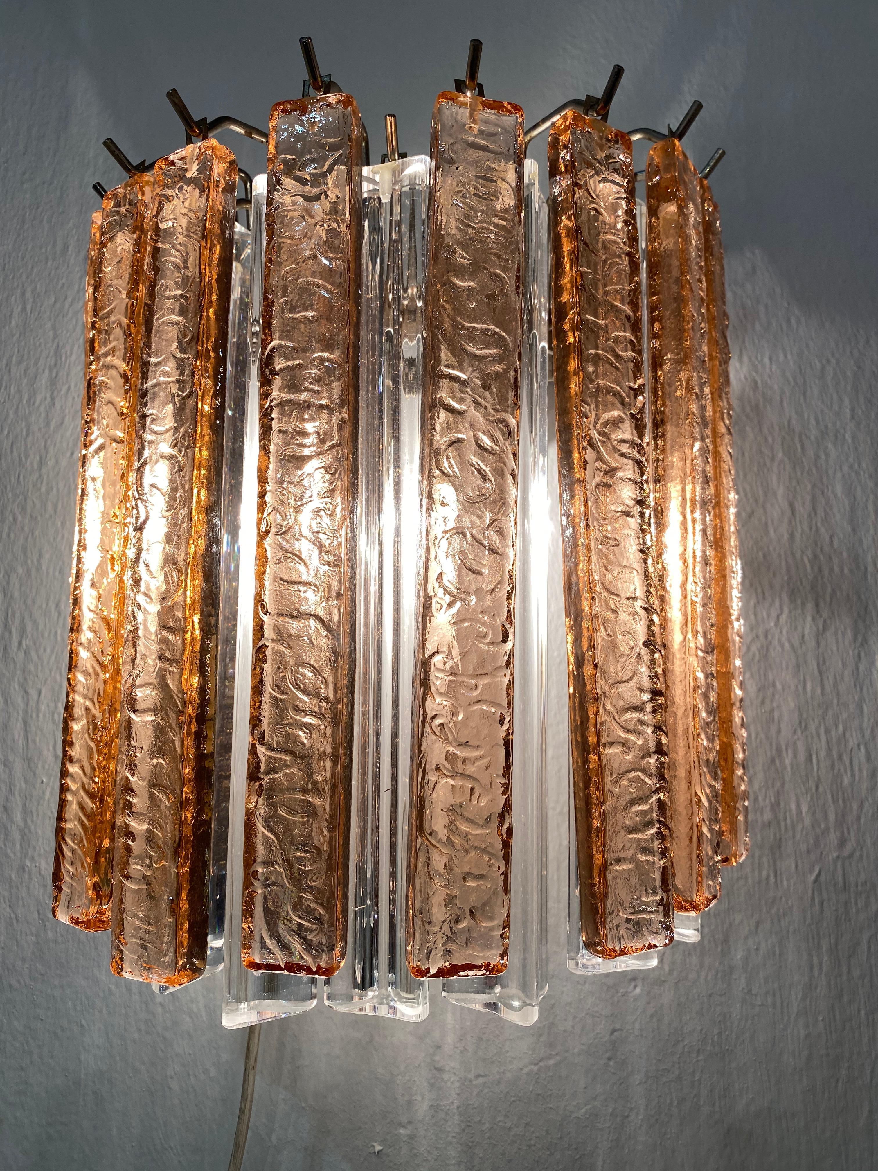 Fantástico par de apliques vintage de Murano compuestos por 19 prismas de cristal de Murano (triedri) para cada aplique en un marco de metal cromado. La forma de los apliques es de columna. Los vasos son de color rosa (10 piezas) y de hielo (9