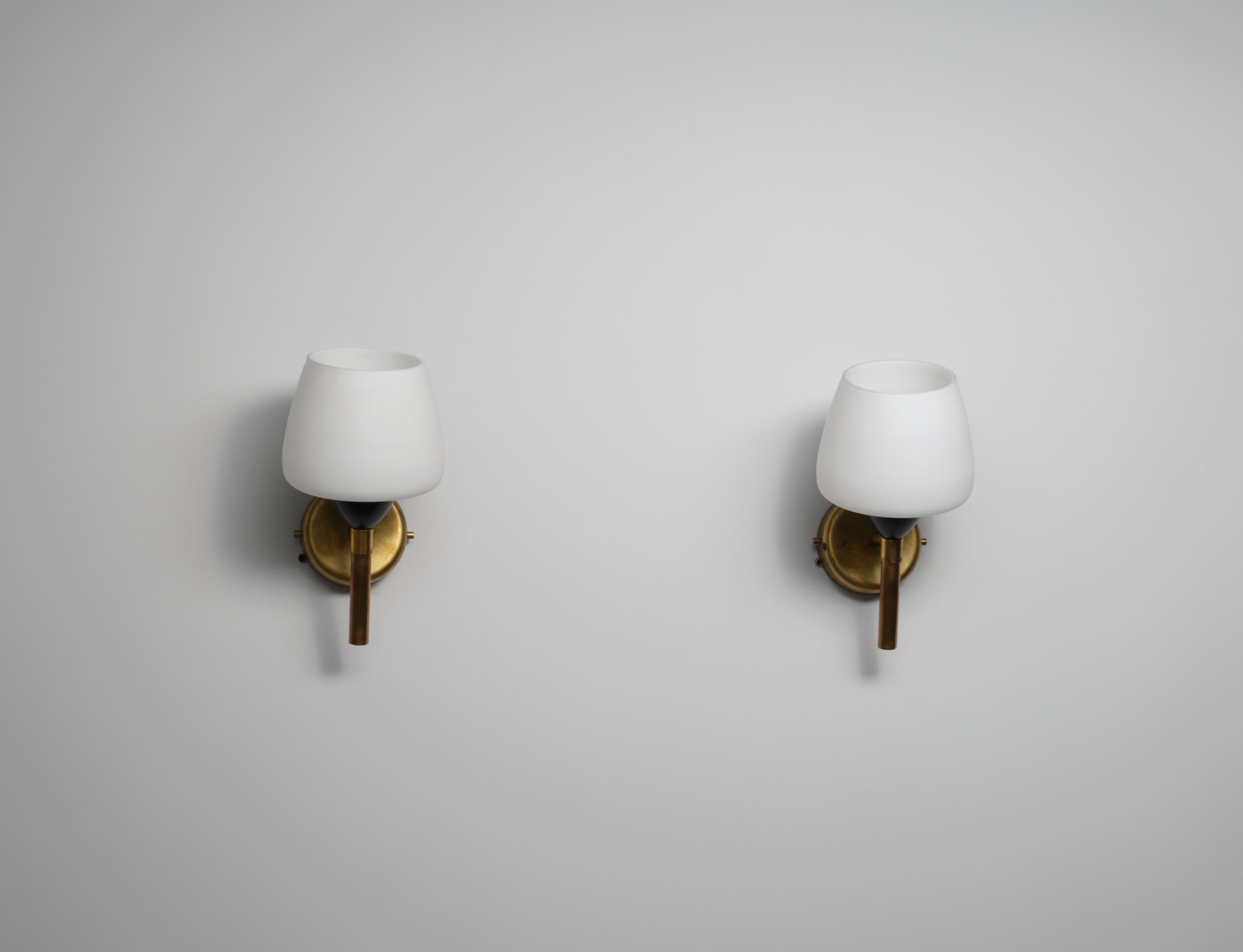 Pair of wall sconces designed and produced in Italy during the 1950s.
Each sconce features a brass structure combined with black lacquered metal and a white opaline glass shade.
The design is essential and linear, suitable for modern and elegant