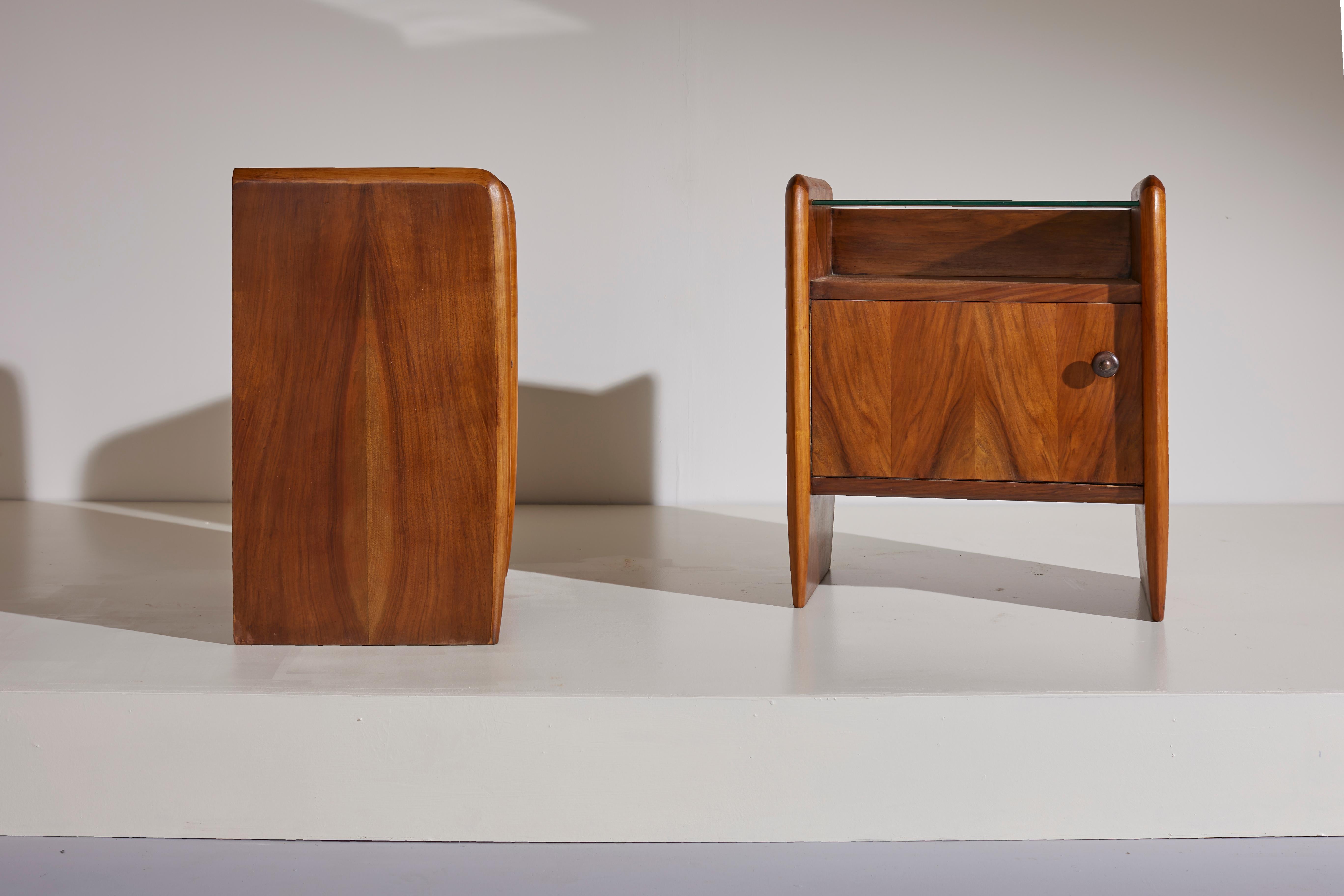 A pair of Italian midcentury nightstands/bedsides made in walnut and glass in the style of Osvaldo Borsani.
Their classical but extremely clean lines, their rounded profiles and their thin legs creates an elegant design which could fit both, modern