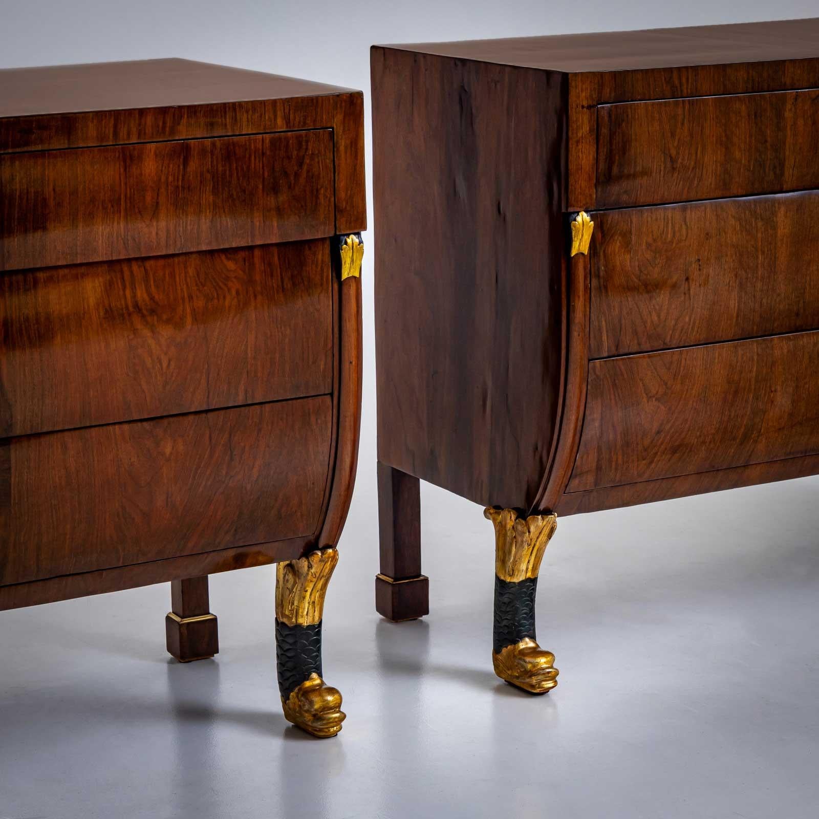 Coppia di grandi cassettiere italiane a tre cassetti impiallacciate in noce. I commodes hanno una forma insolita, arrotondata nella parte inferiore e poggiano su piedi a zampa di leone patinati in verde e oro nella parte anteriore. I pilastri sono