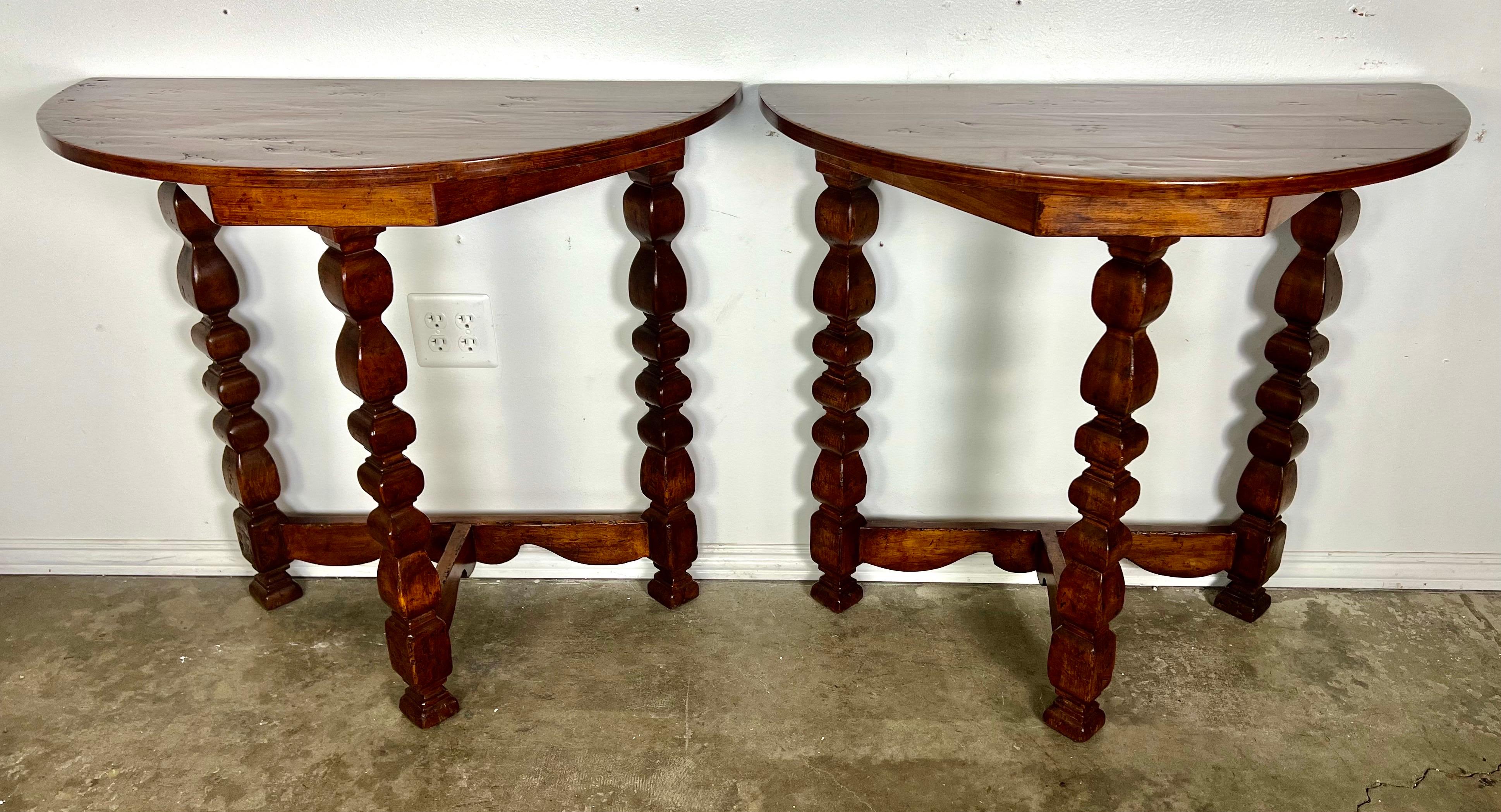 Pair of 1930's Italian demi-lune consoles with a distinctive design featuring turned spindle legs.  There is a bottom stretcher that connects the legs. The walnut has a rich tone and a beautiful patina.  