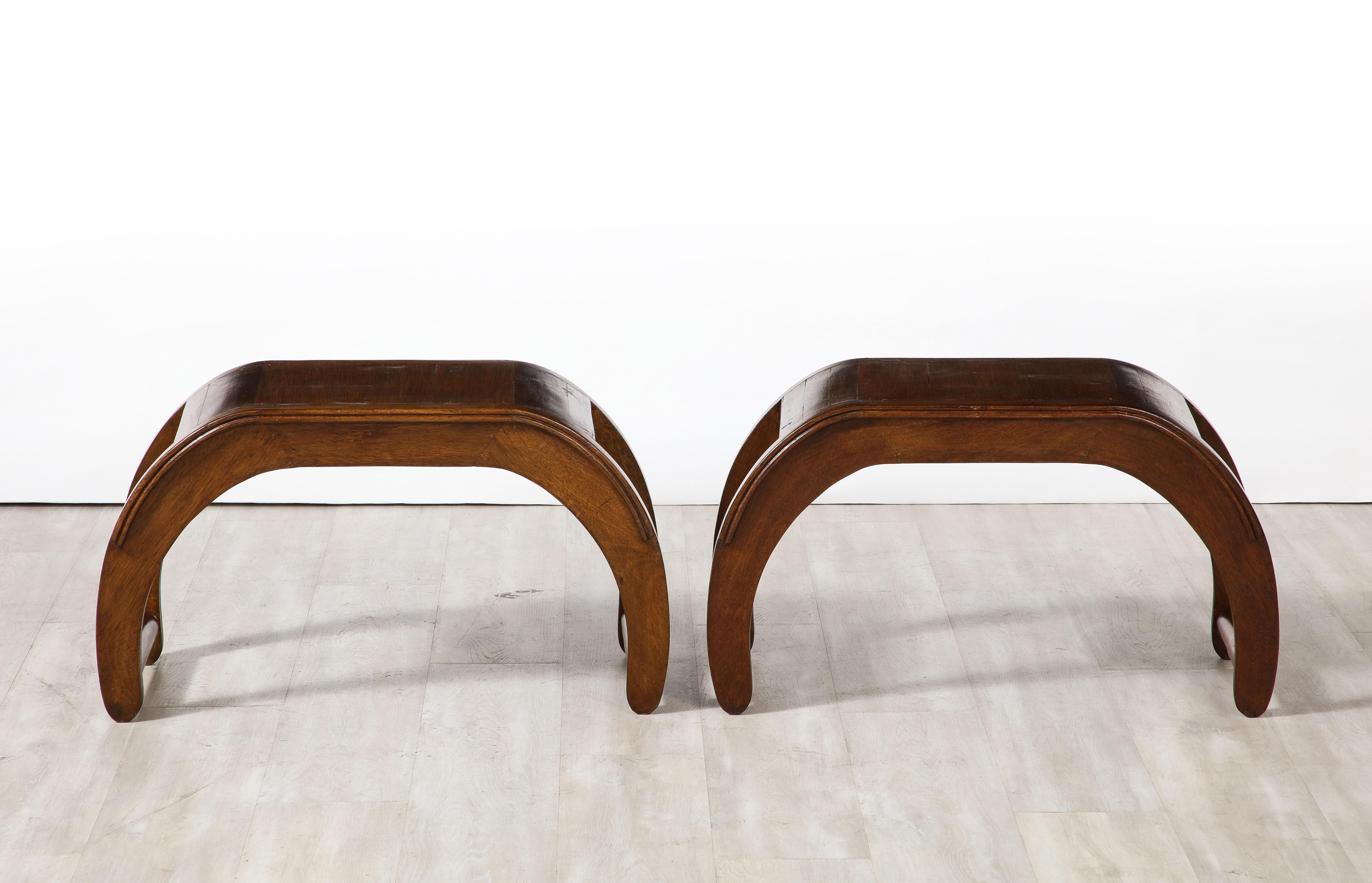A pair of highly unique Italian walnut benches with a striking elliptical shape, the seat wide and comfortable and the base with turned stretchers connecting the legs. With an embossed metal mark with the initials GJ, the pair were likely custom