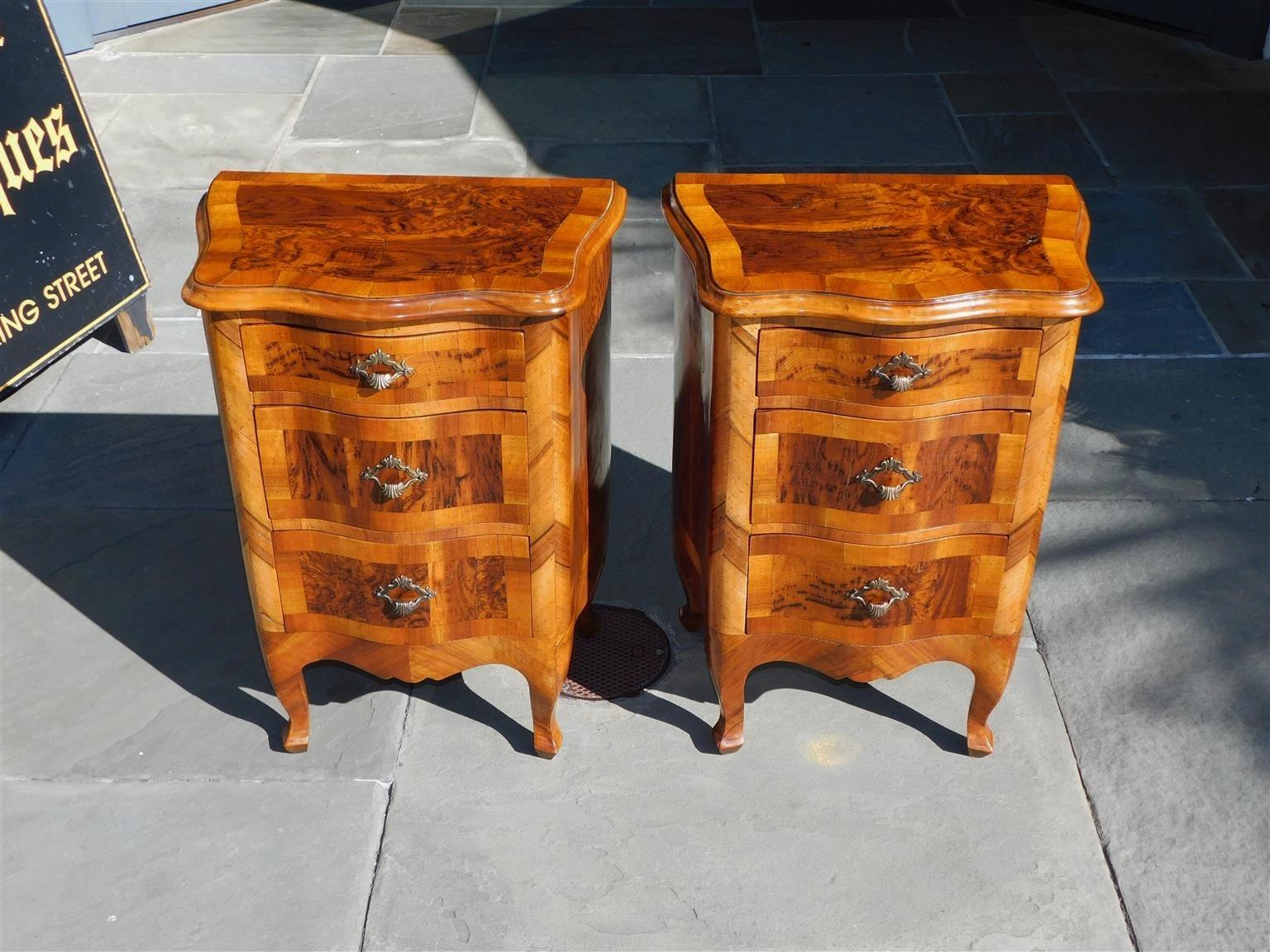 Pair of Italian burl walnut serpentine inlaid three graduated drawer commodes with the original floral shell brasses, flanking serpentine skirts, and resting on the original cabriole legs. Mid 19th century.
