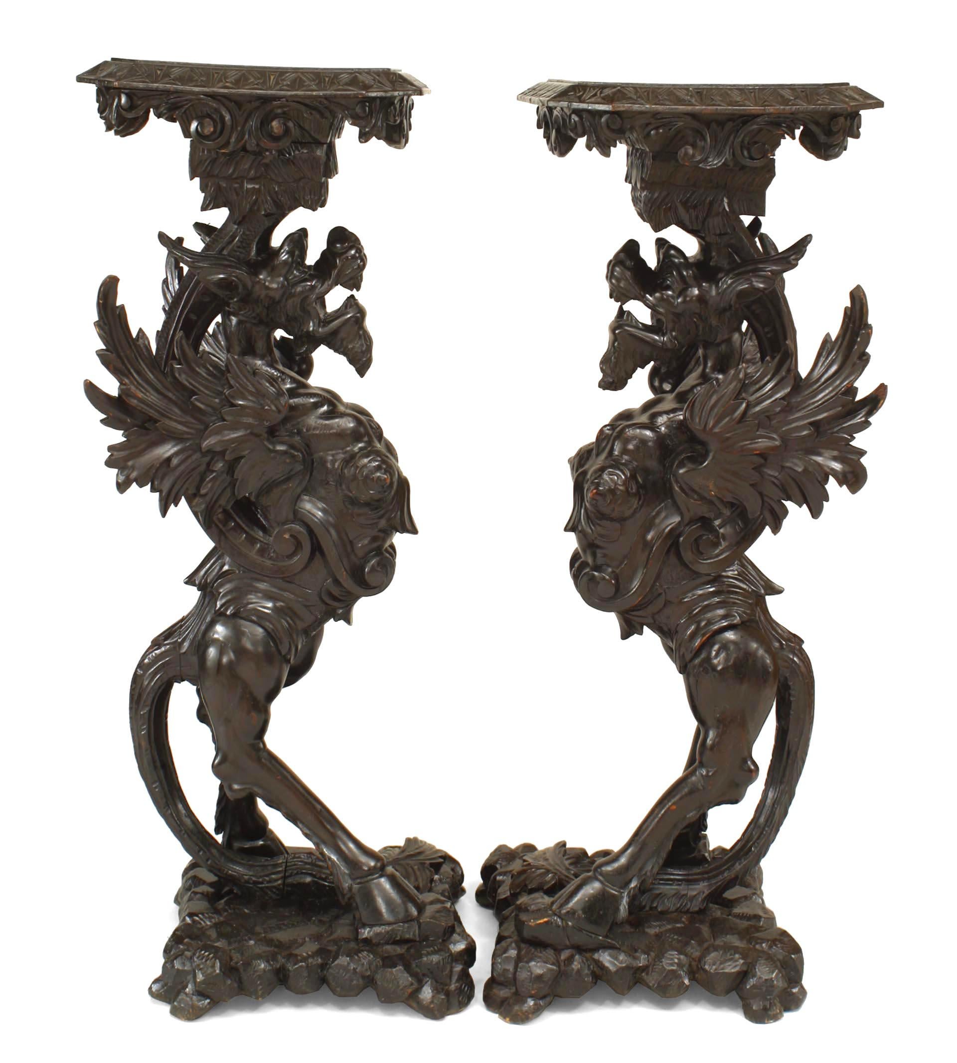 Pareja de pedestales italianos (s. XIX) de nogal tallado con base de grifo alado sobre base cuadrada.
