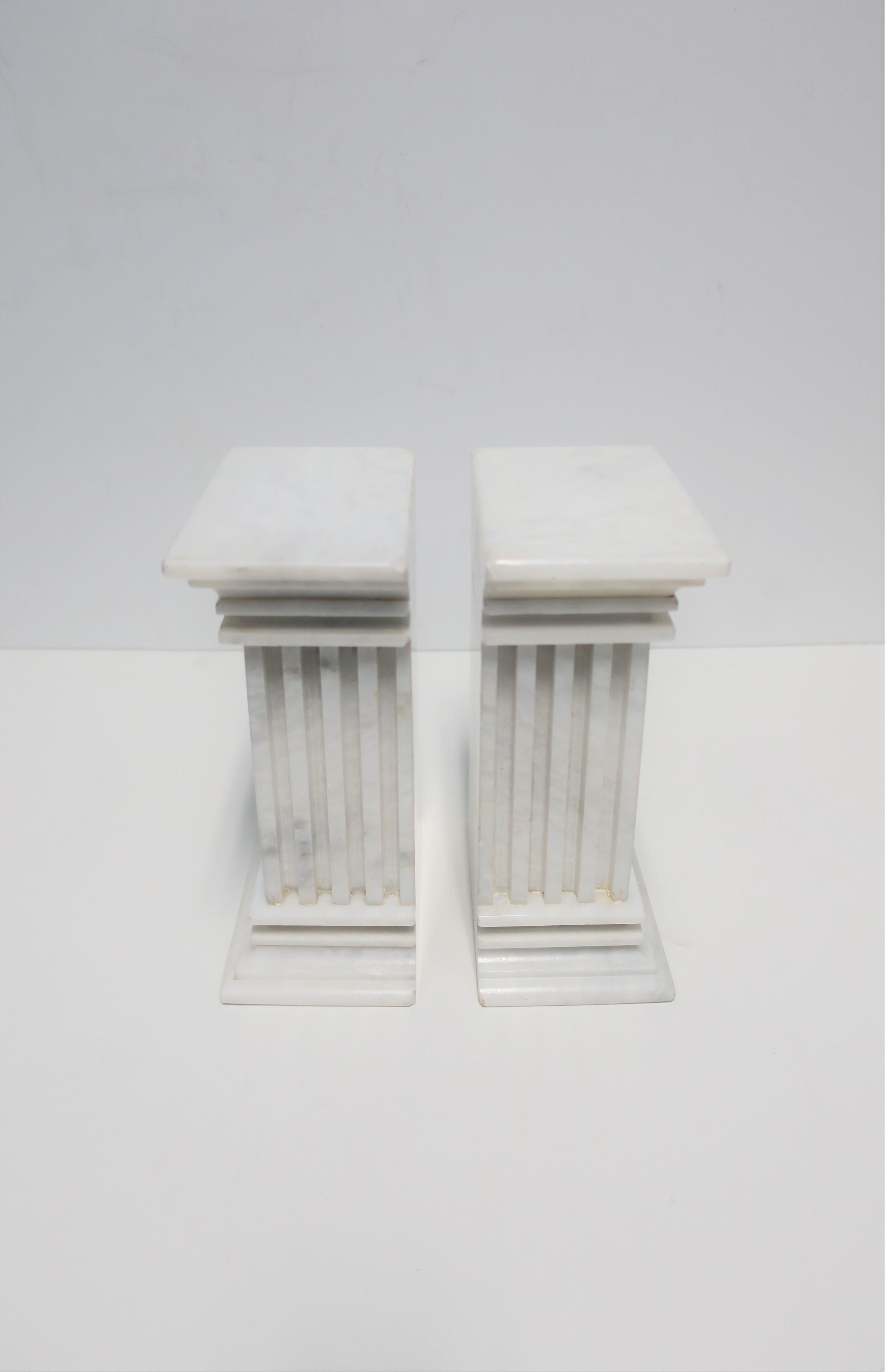 A beautiful and substantial pair of Italian white marble column pillar bookends, circa 20th century, Italy. Column architecture is in the style of the 'fluted non-tapered'. Marble is predominantly white with very light traces of grey veining. 

Each