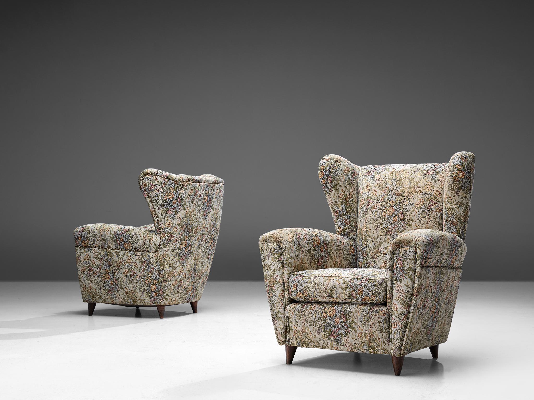 Large wingback armchairs, multicolored fabric upholstery, and wood, Italy, 1950s.

This classic Italian wingback armchair has a round shape that emphasizes its comfortableness. It has a high back and gracious wings that contains dramatized pointed