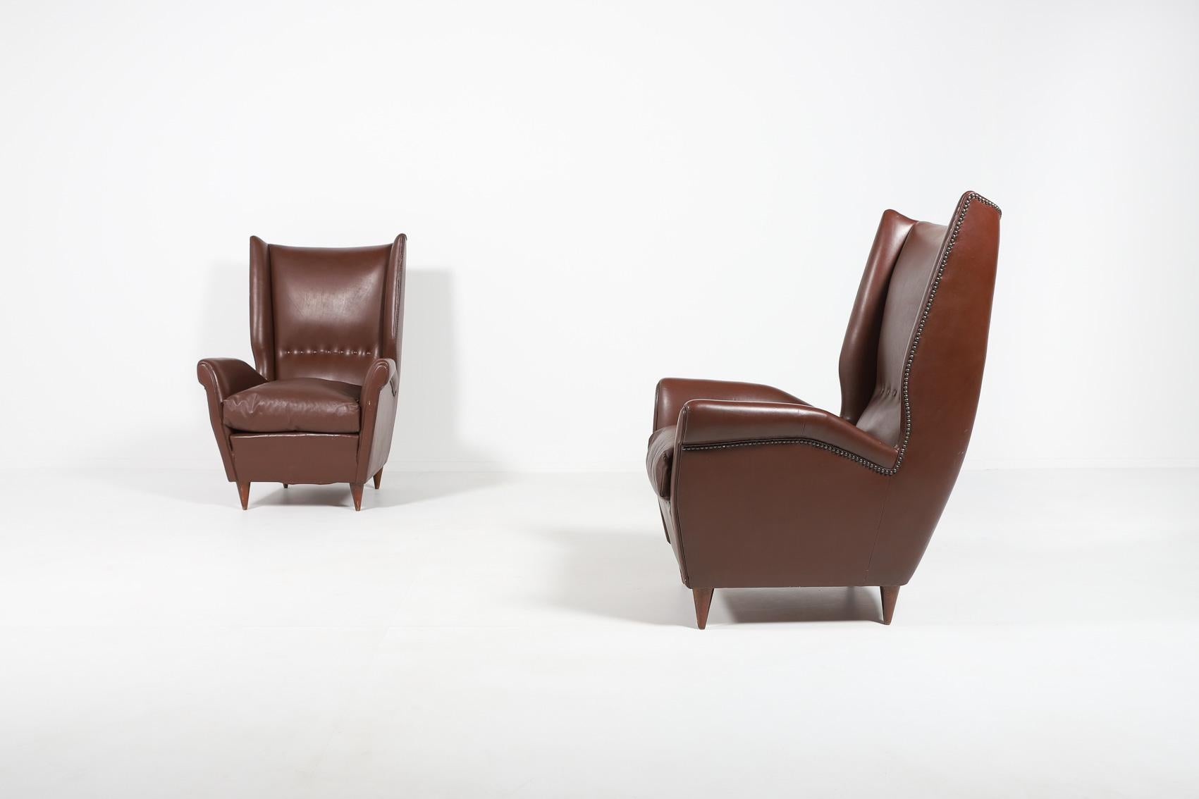 Paire de 2 spectaculaires fauteuils de salon en cuir marron sur pieds en bois teinté, coussins d'assise détachés. La maîtrise de l'architecture italienne et de l'icône du design Gio Ponti, aristocratique et épurée à la fois.

Condit
Bon, signes