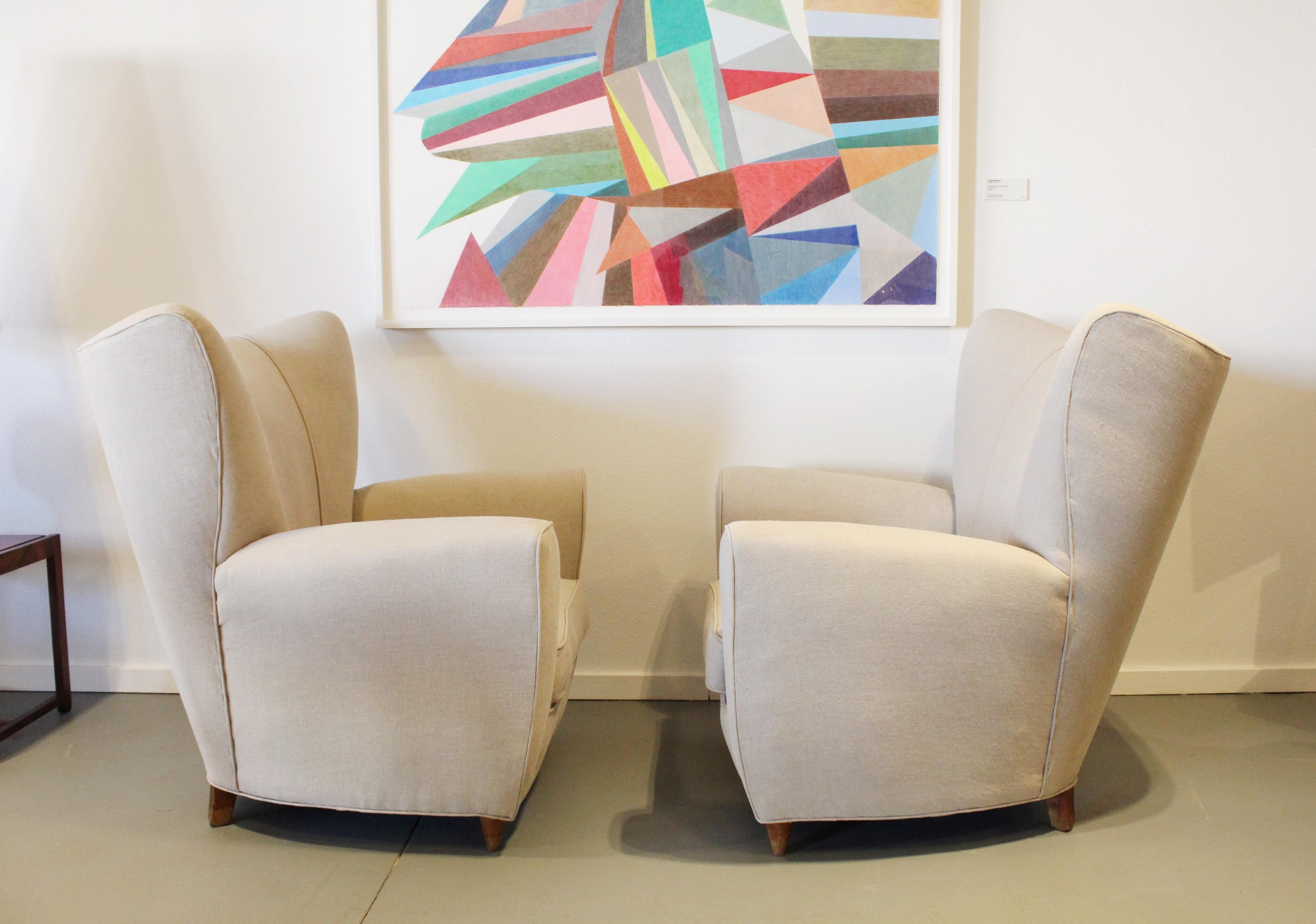 Gorgeous early 1950s Italian Mid-Century Modern Wingback chairs upholstered in a an incredible stone linen. Chairs have patina on the wooden feet and have been left as is which are beautiful. Chairs are reminiscent of Gio Ponti, Guglielmo Ulrich and