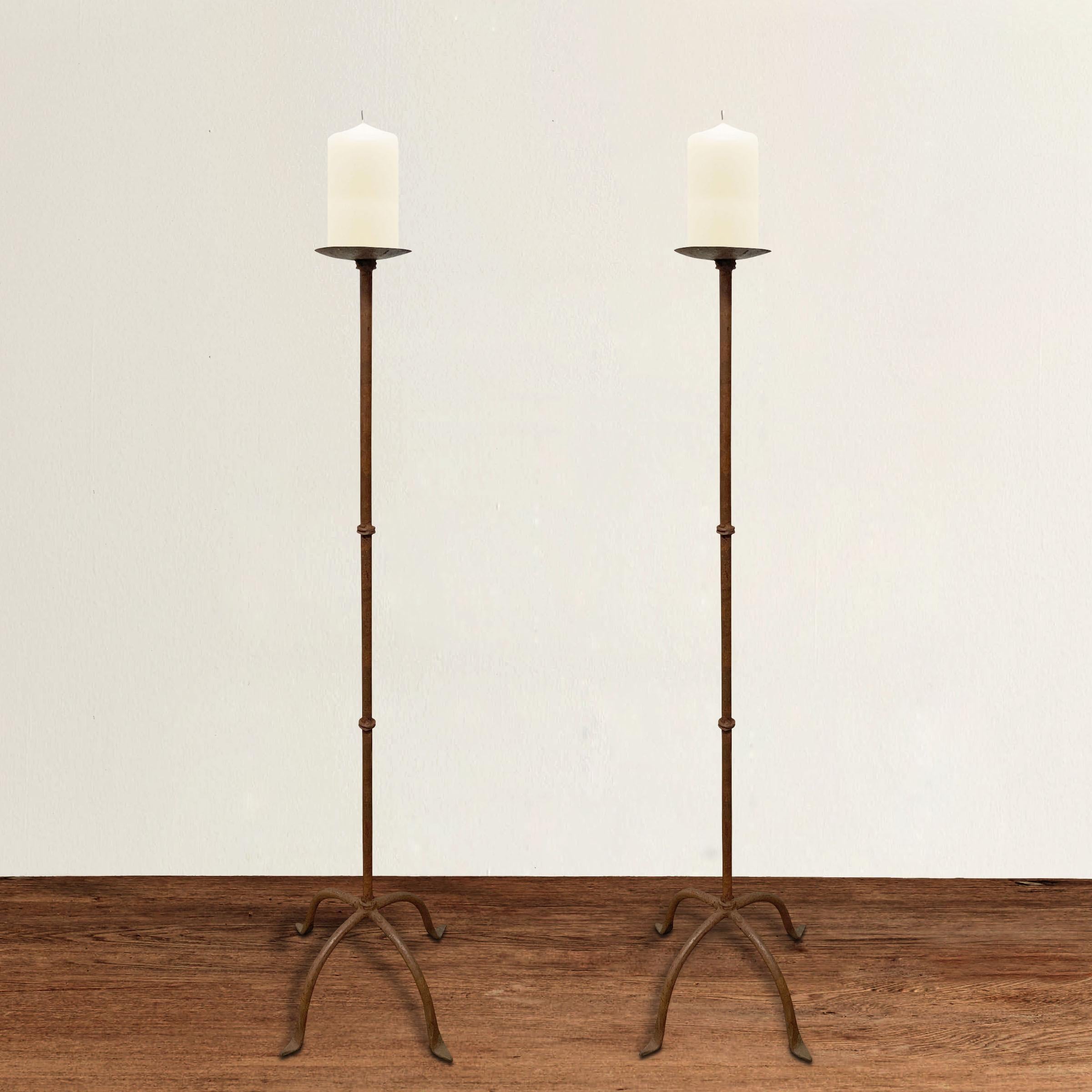 A pair of 20th century Italian hand-wrought iron candle prickets, each with four curved legs ending in pad feet, and several circular iron 'knuckles' running up the stems.