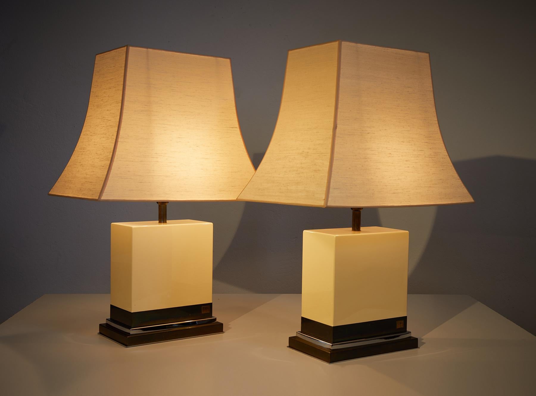 Paire de lampes de table laquées ivoire par Jean-Claude Mahey, France 1970-80.

La partie supérieure des lampes est composée de bois laqué ivoire en très bon état et la base est composée de laiton et de chrome. 

Les deux lampes sont signées par