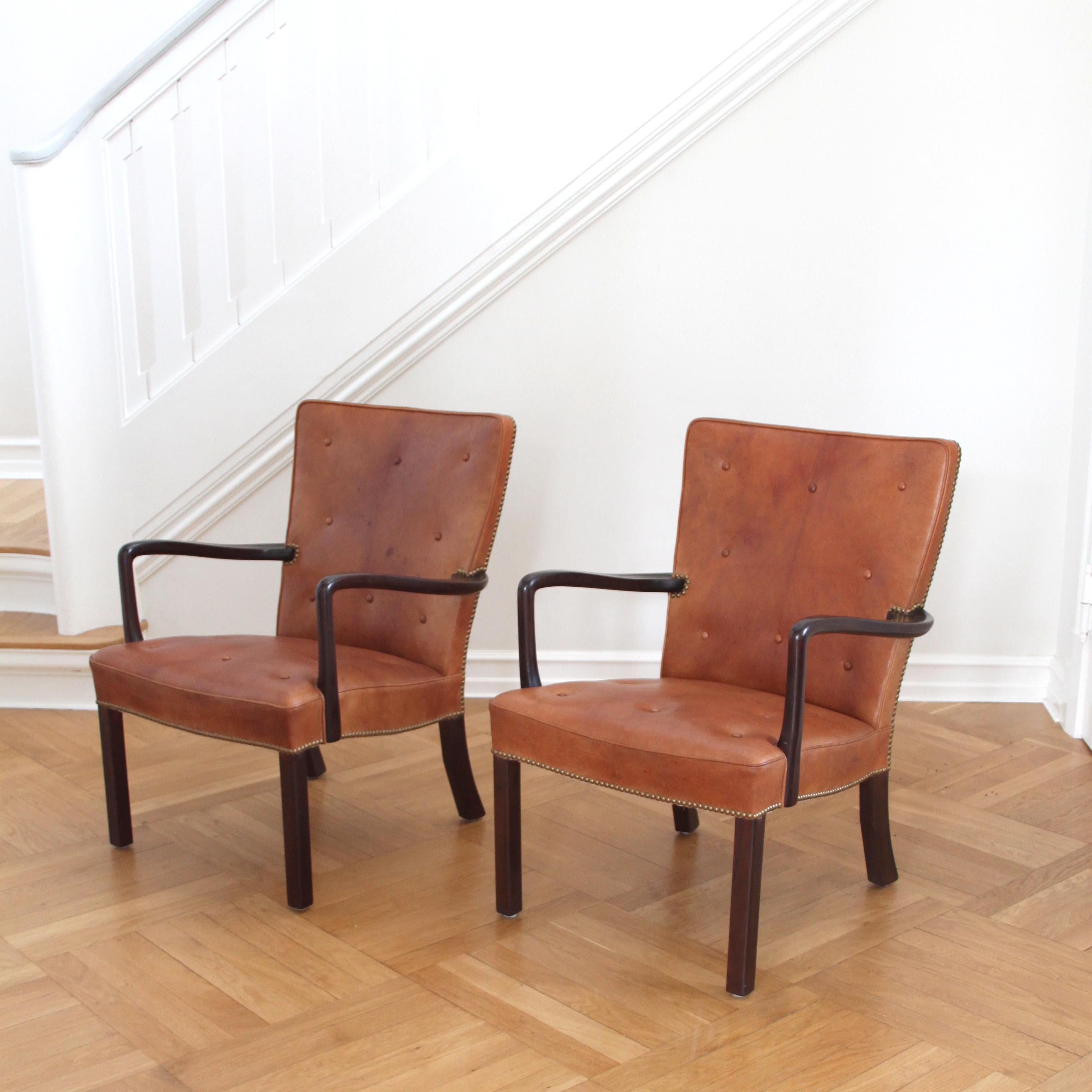 JACOB KJÆR - SCANDINAVIAN MODERN

A beautiful pair of lounge chairs, designed and manufactured by cabinetmaker Jacob Kjær (1896-1957).

Materials: Dark stained mahogany and upholstered in Nigerian leather with buttens and brass