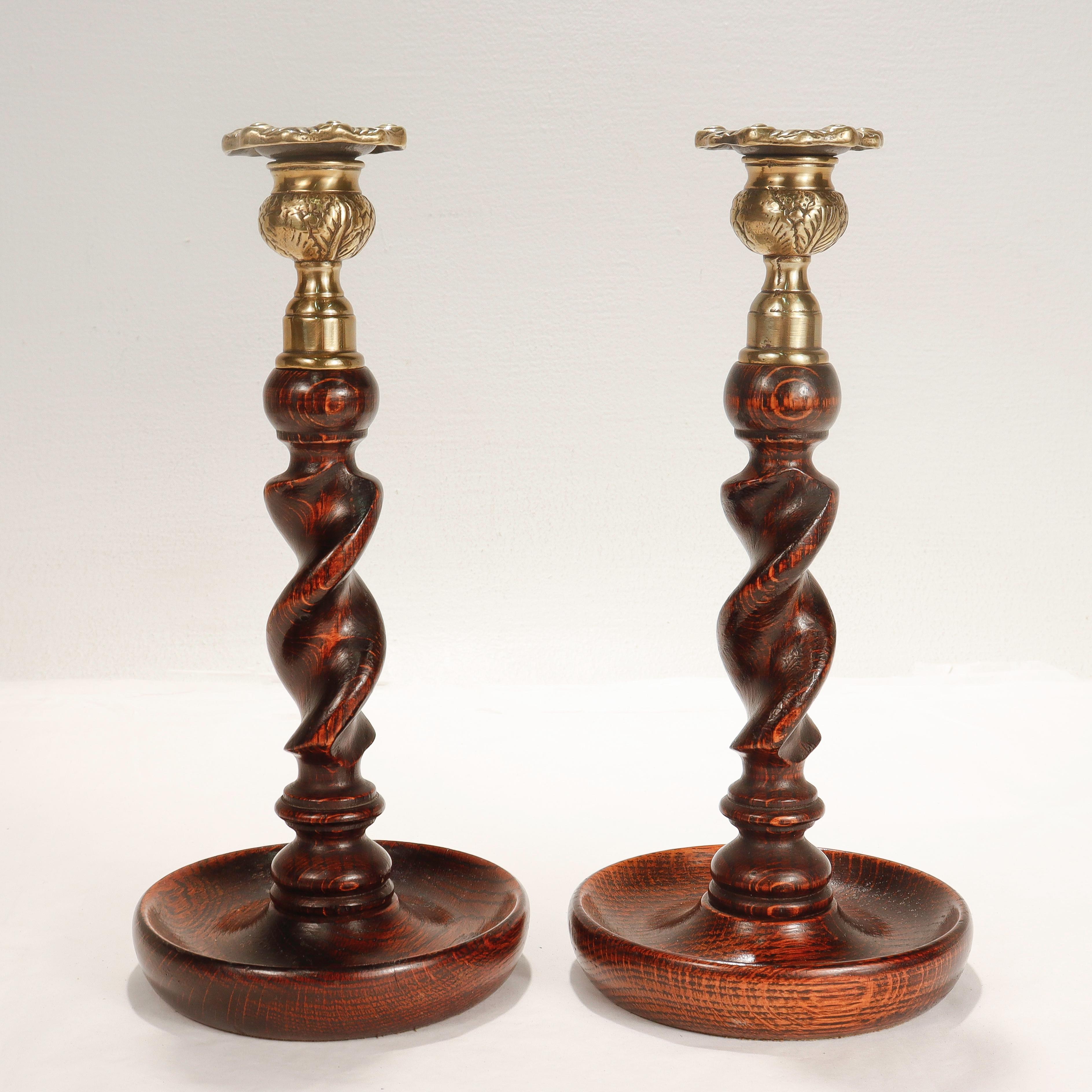 A fine pair of Jacobean style candlesticks.

In turned oak with upturned bases supporting barley twist shafts and cast brass candle cups & bobeches.

The bobeches are threaded and removable and the bases have aged green felt pads.

Simply a