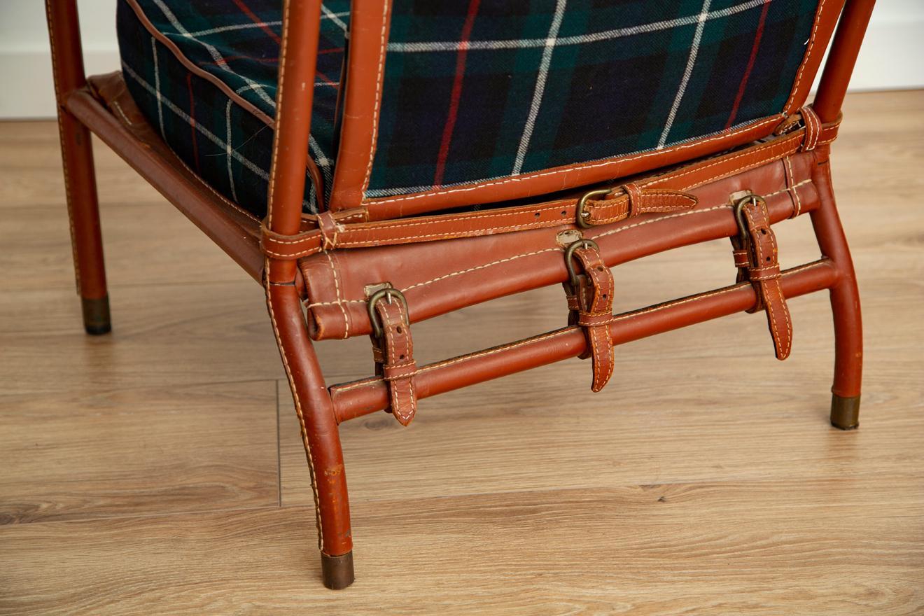 Rare pair of Jacques Adnet lounge chairs with new tartan plaid wool upholstery. Original brown handstitched leather in good vintage condition.
  