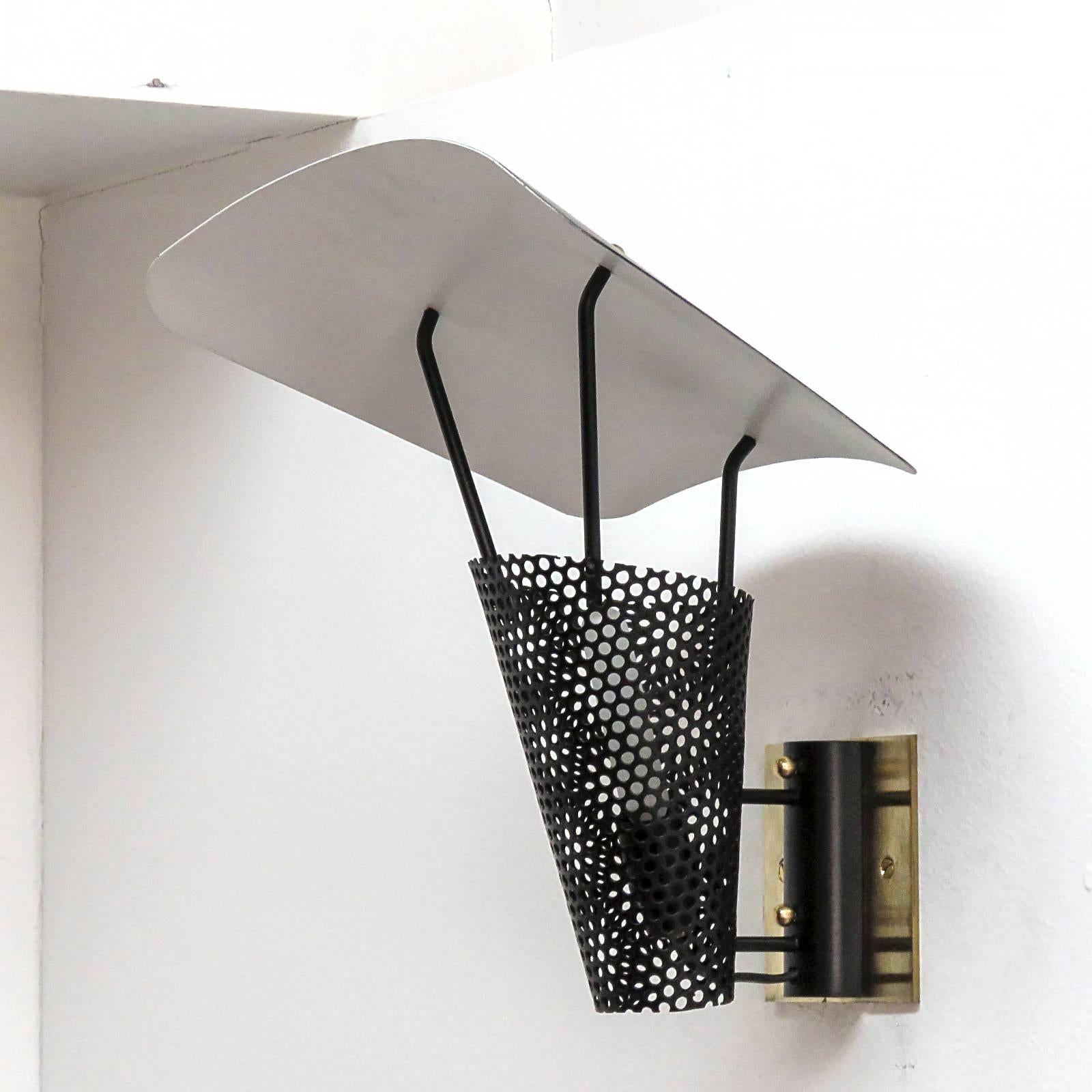 Iconic pair of French wall lights by Jacques Biny in black and white enameled and perforated metal with brass accents and solid brass back plates, one E12 socket per fixture, max. wattage 60w each, bulbs provided as a one time courtesy.