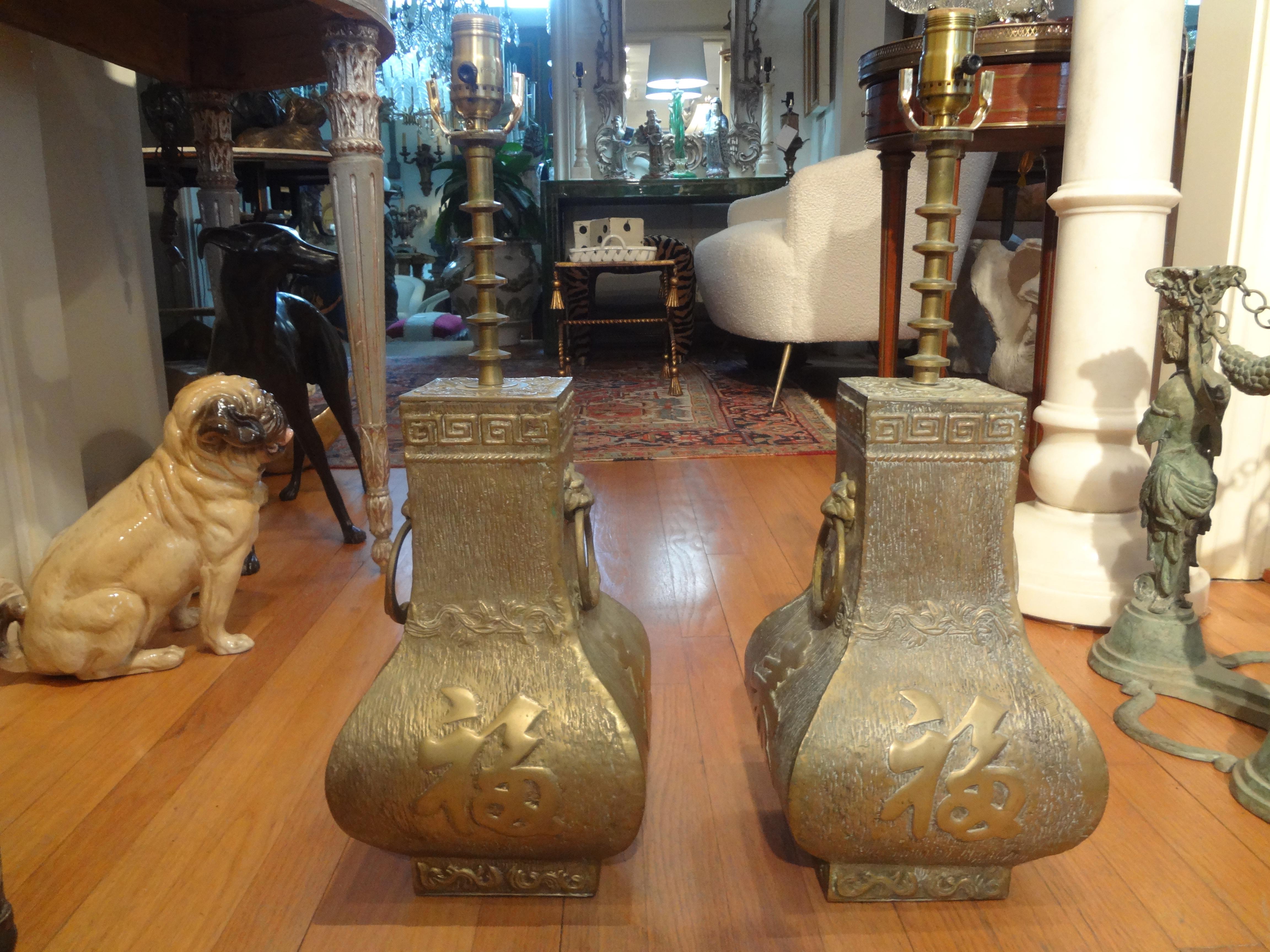 Pair of James Mont Asian Modern brass lamps. These stunning heavyweight Hollywood Regency brass lamps feature Chinese characters, Greek keys and lion heads handles. This great pair of midcentury brass lamps have been newly wired with new sockets and