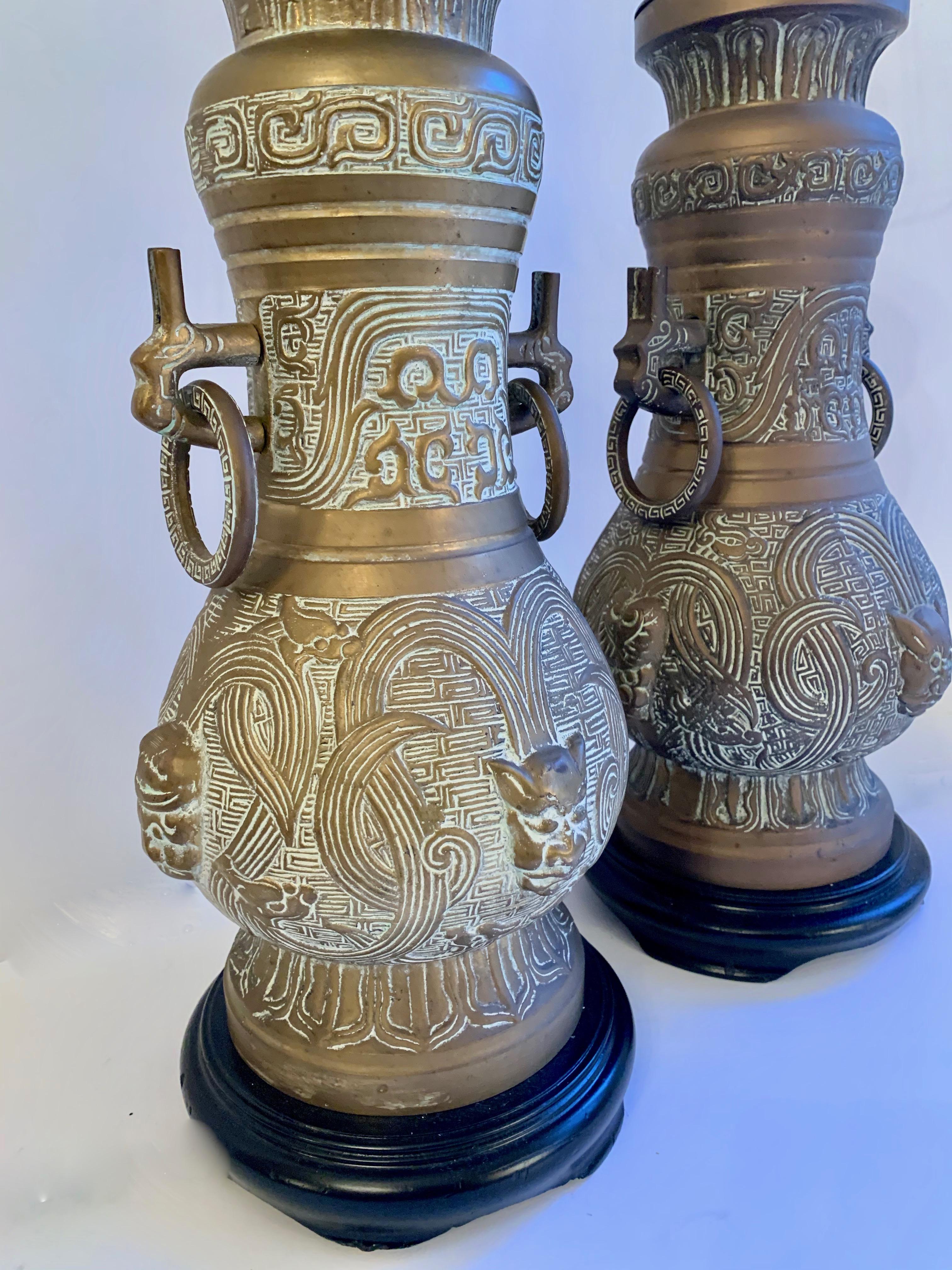 James Mont style bronze Asian urn lamps with ring handles. A wonderful pair.
Includes the black shades with gold lining - we are of course glad to create new shades using COM as well. 

The bases and caps of wood have been freshly lacquered.