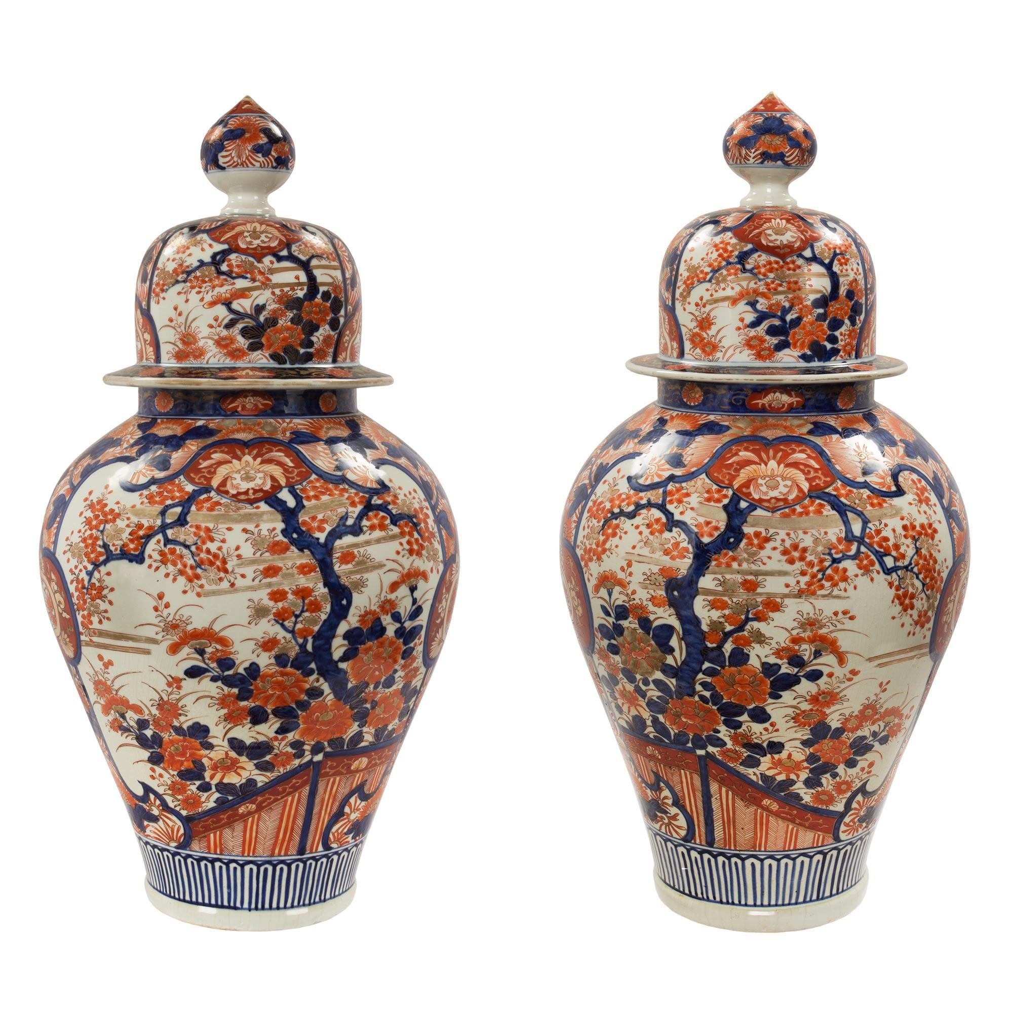 A pair of beautiful and large scale Japanese 19th century Imari lidded urns. Each urn displays most elegant traditional floral hand painted designs with finely detailed and most charming scenes. Above is the removable lid with a striking circular