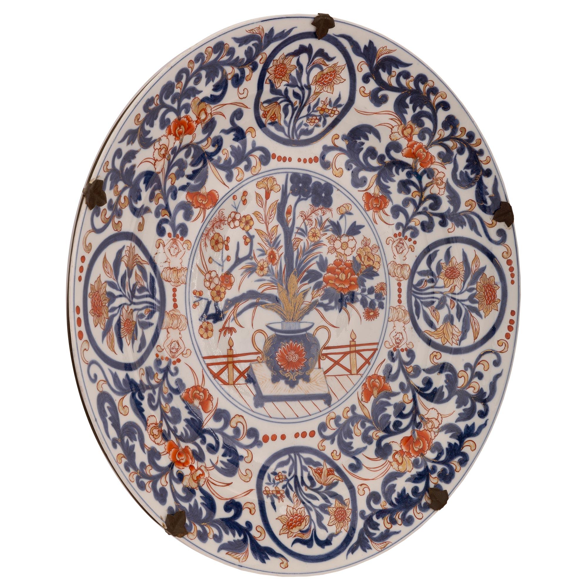 Un hermoso y decorativo par de platos japoneses de porcelana Imari del siglo XIX. Cada plato circular muestra llamativos diseños foliados finamente detallados con flores en una urna en el centro en los tradicionales colores rojo y azul con detalles