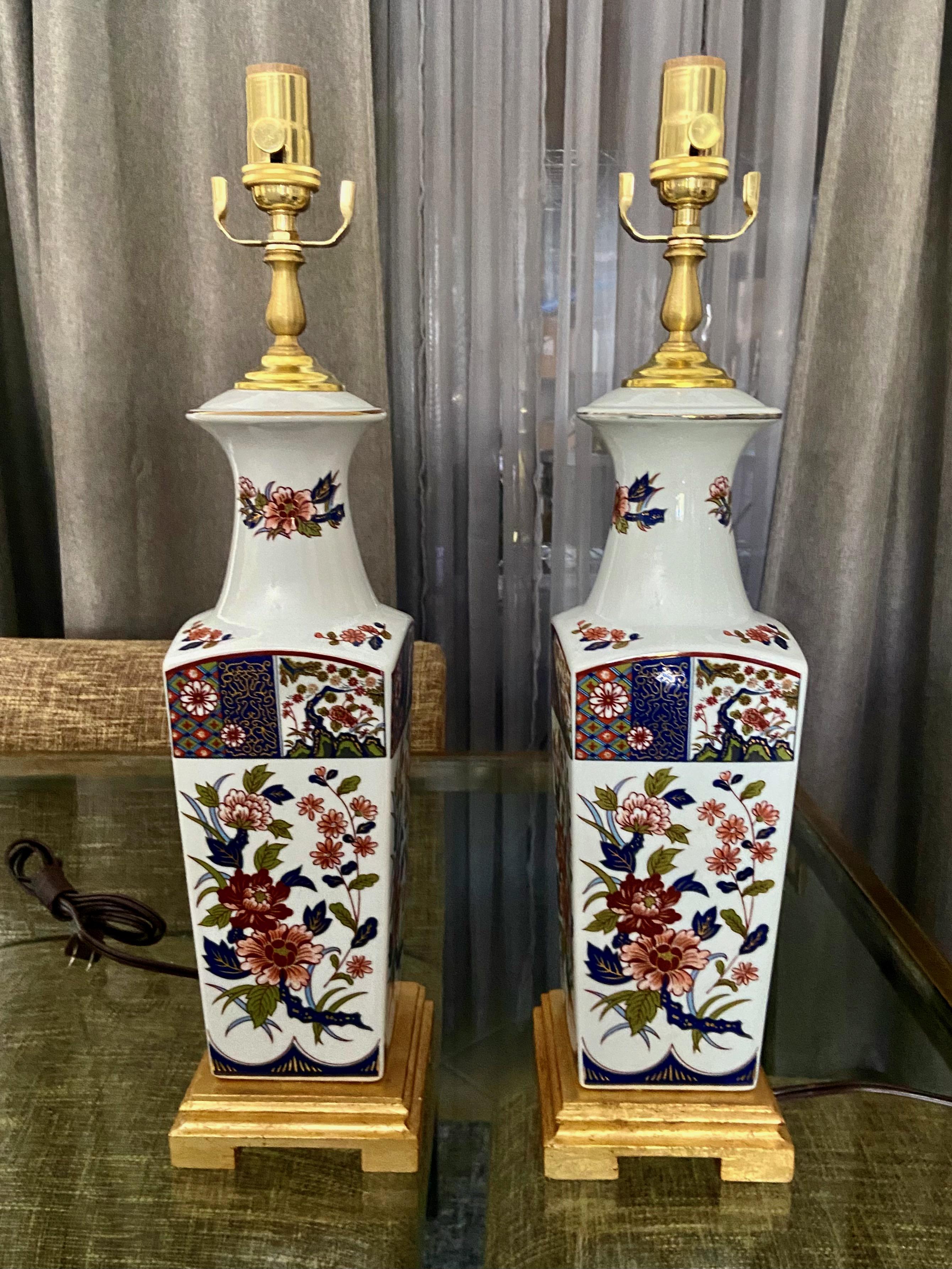 Pair of Japanese Imari porcelain square shape vases mounted on giltwood bases. The colors are a rich red and blue, the design is a classic flower and leaf motif.  Newly wired with new brass 3 way brass sockets, brass fittings and cords. 
Vase