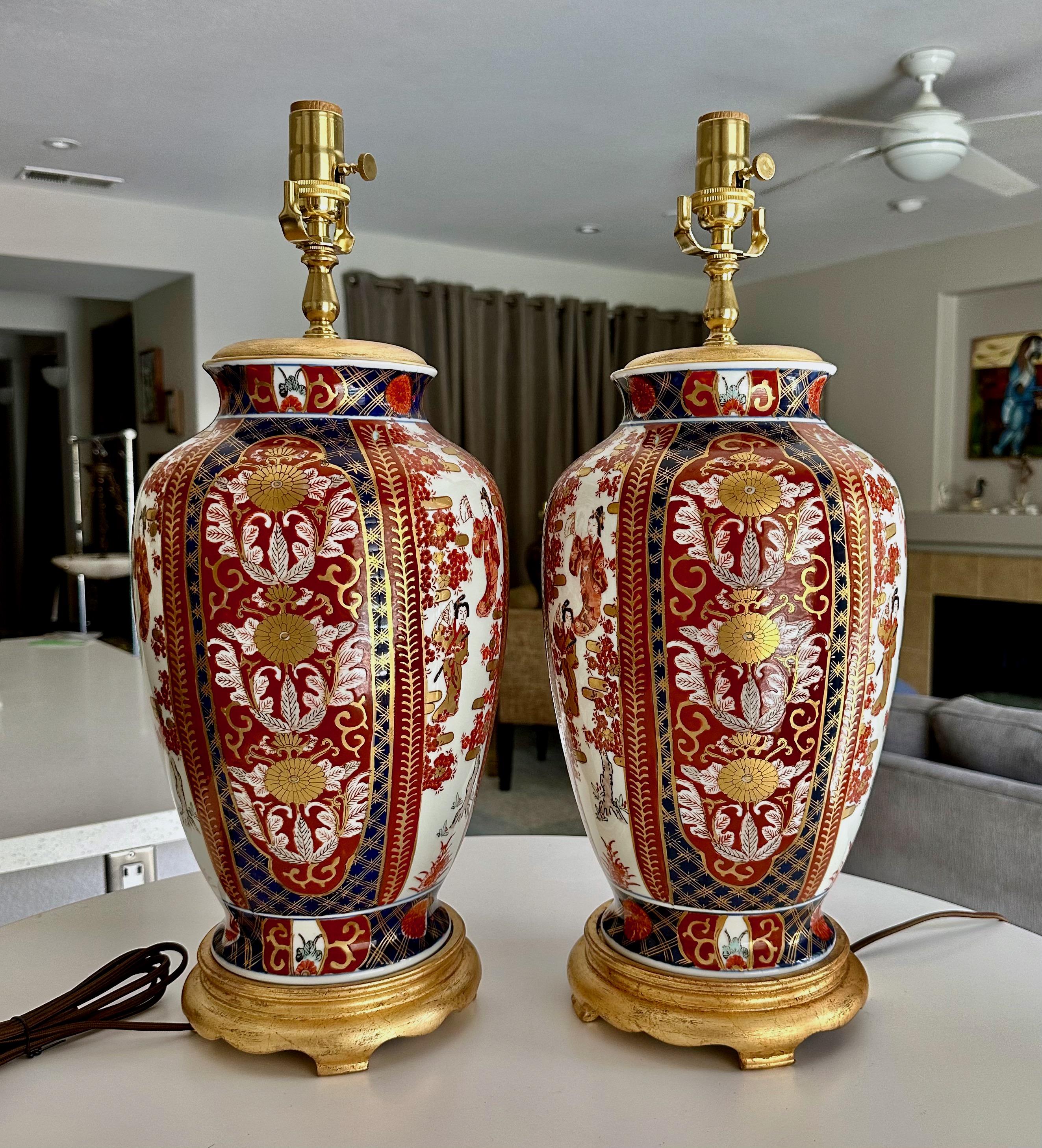 Pair of Japanese Imari porcelain vases mounted on giltwood bases, from the 50's 
possibly older unmarked. The colors are a rich burnt orange and dark blue with gold outlining, the design has figural images with classic flower and leaf motif. Newly