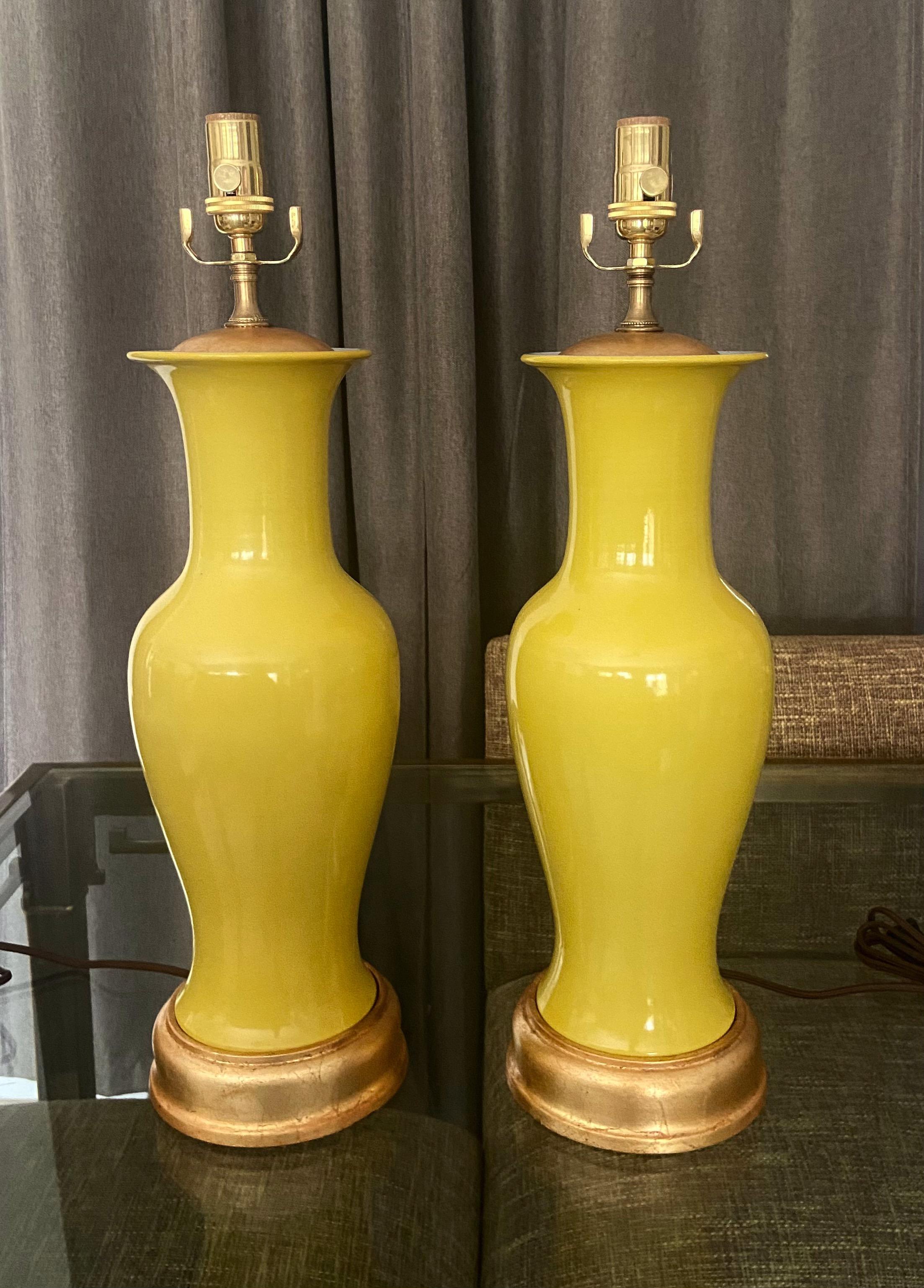 Paire de vases de forme balustre en porcelaine de couleur jaune d'Asie montés sur des pieds de lampe en bois tourné et doré. Nouvellement câblé avec de nouvelles prises en laiton à 3 voies et des cordons en rayonne. La partie vase mesure 16