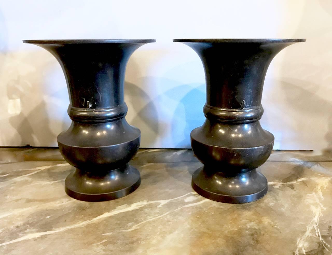 This is an iconic pair of 19th century Japanese bronze urns in archaic form. The proportions of the urns make them ideal for book shelf detailing and they are perfect for displaying orchids. Both urns are in very good condition; the side removable