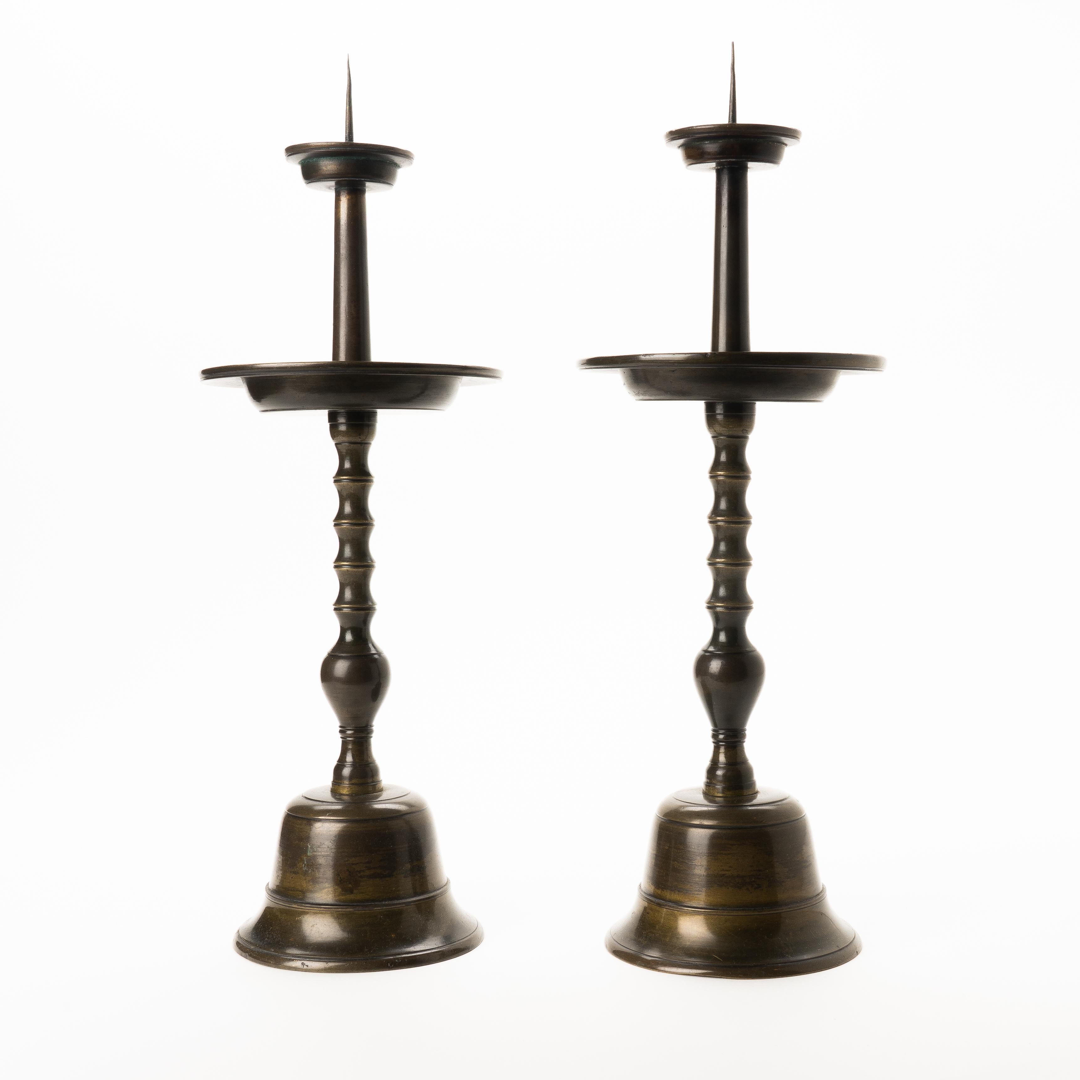 Pair of Japanese cast and patinated bronze altar pricket candle sticks with candle cup above a mid shaft drip pan on a bell shaped base. Cast threaded joinery of the shaft to the base.

Japan, early 20th century.